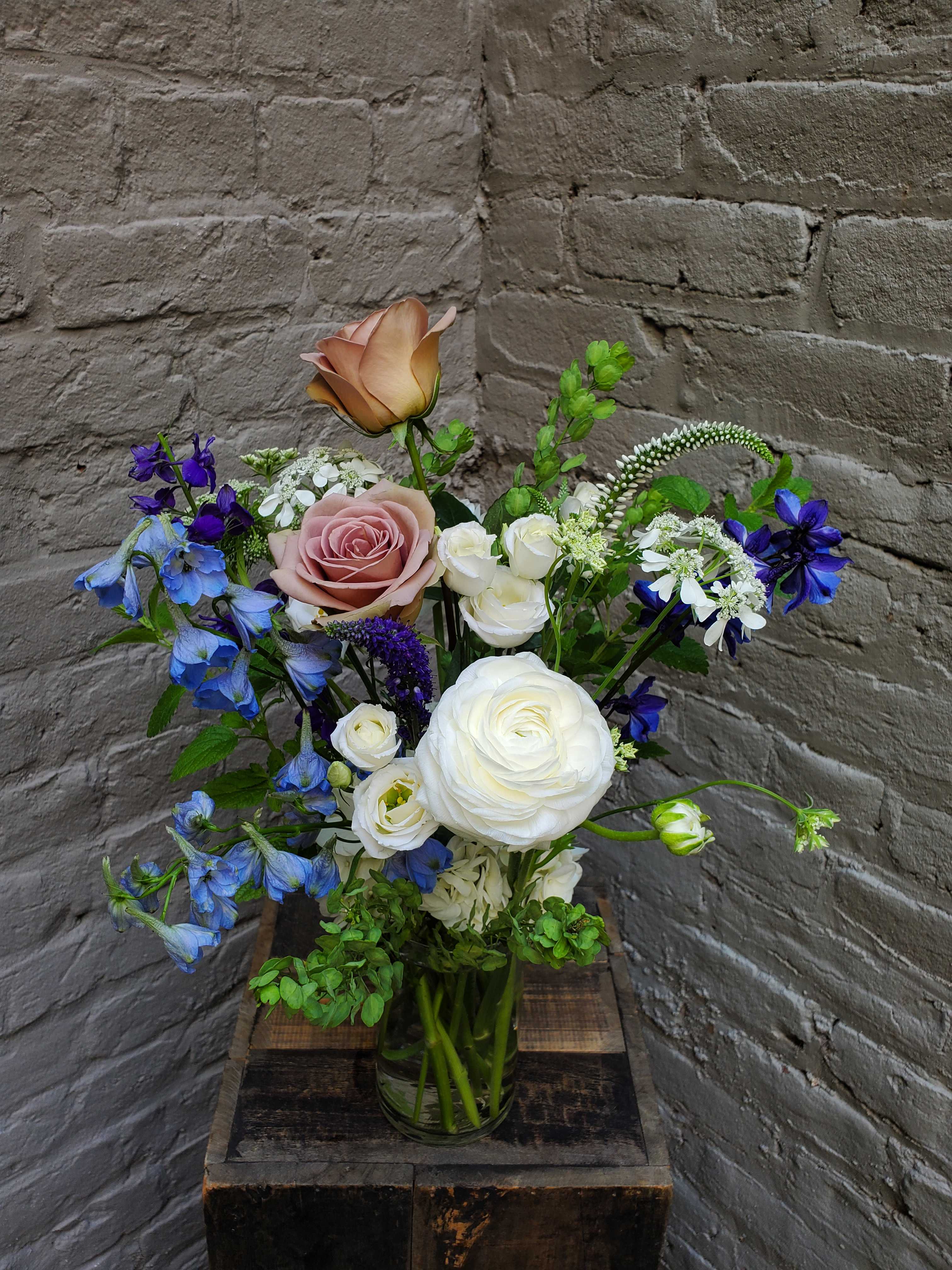 Blue Skies - Sky blue, dusky lavender and cumulus white blooms create a heavenly display in this vased arrangement.  With delphinium, larkspur, roses, and more -- these long and lovely stems may inspire you to reach for the sky!  Arrangement measures approximately 18&quot; tall x 12&quot; wide.