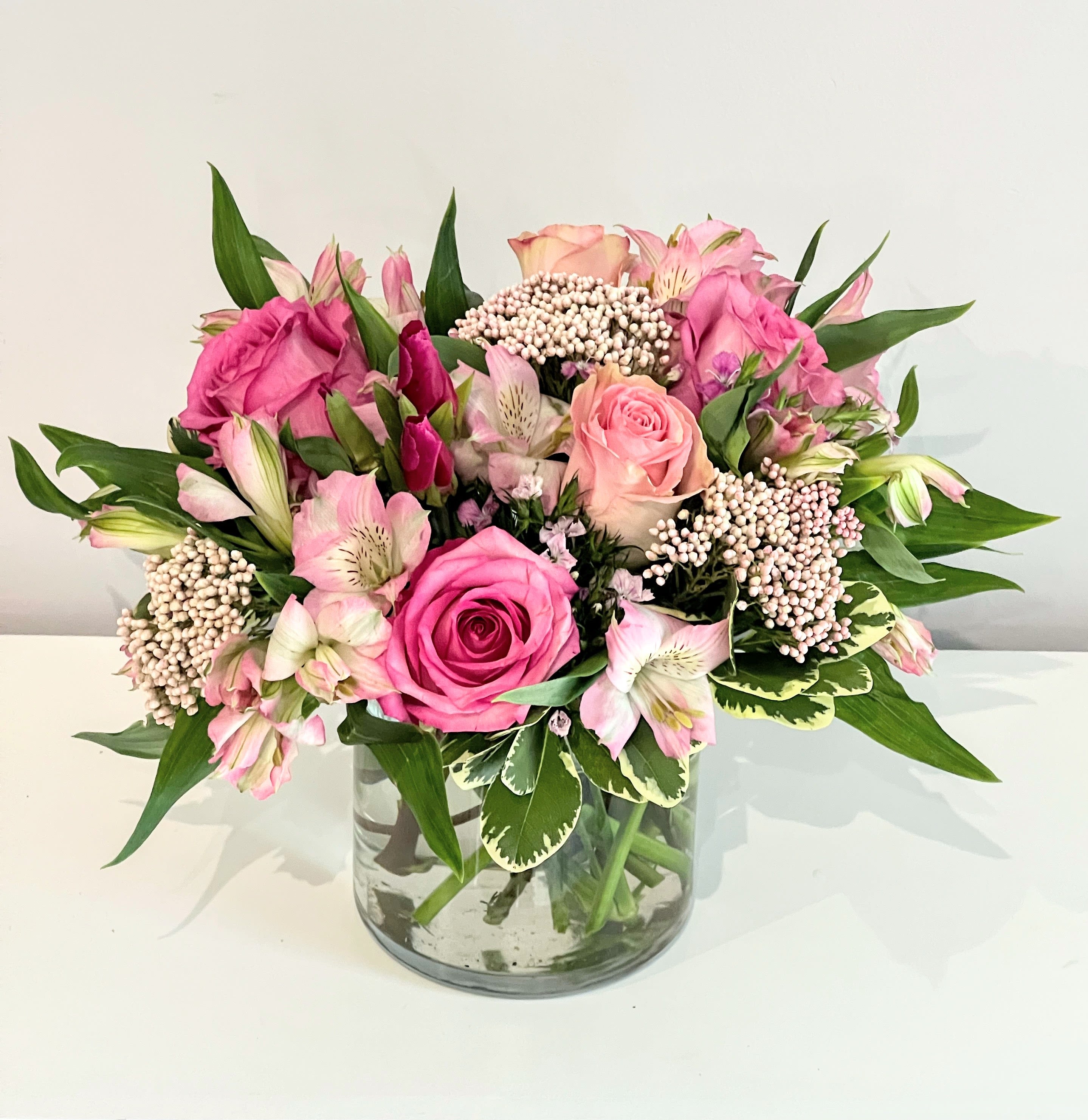 Pinky Promise Pinky Promise - A beautiful all pink bouquet featuring the freshest selection of seasonal blooms like light & dark pink roses, delicate rice flower, pink alstroemeria, & greenery. Arranged low & delivered in a clear glass round cylinder. It's the perfect floral gift for any love & romance occasion, welcoming a new baby girl or for anyone that loves pink! Measures approx. 10" tall and 14" wide Orientation: All around