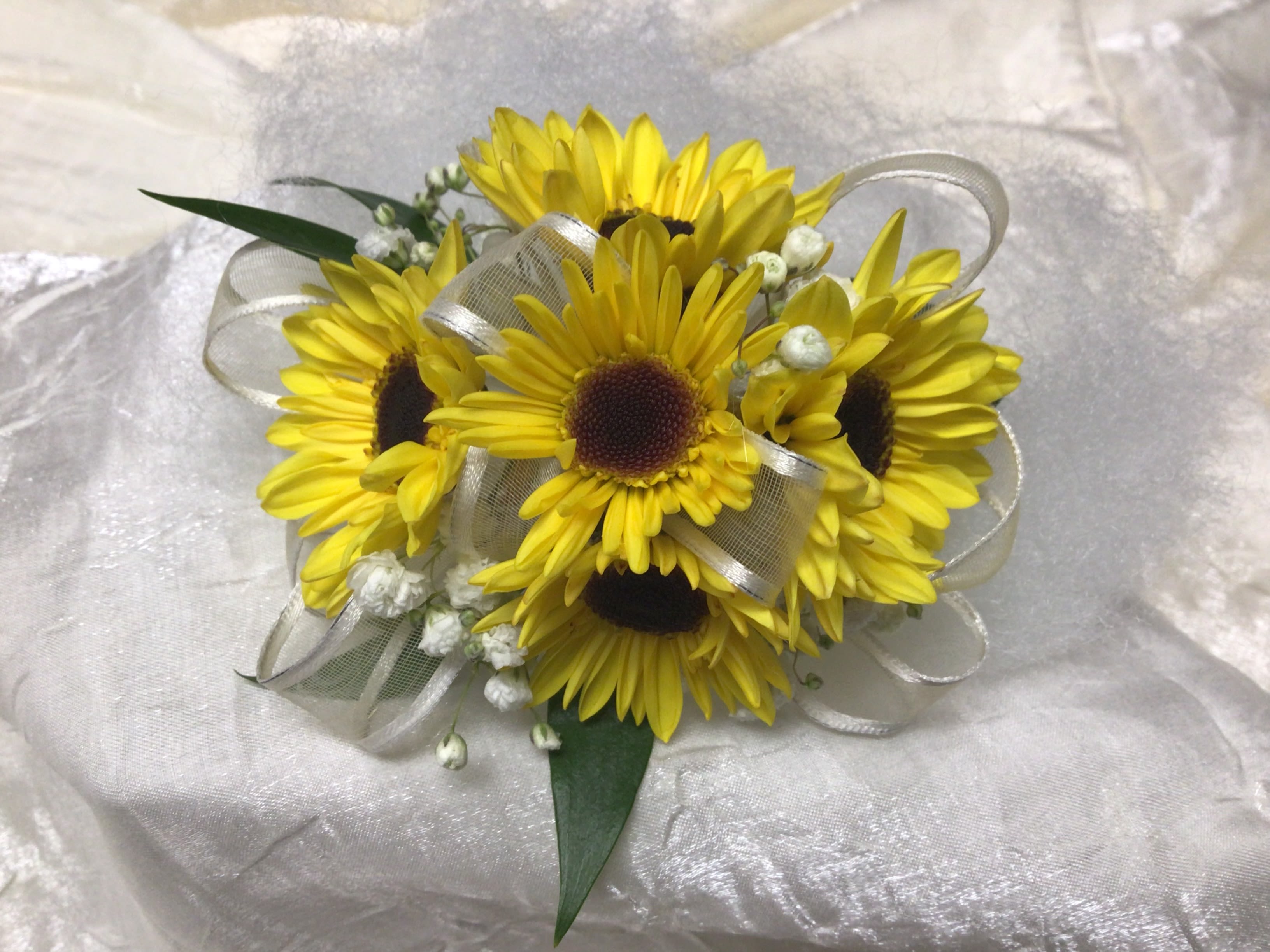 Tiny &quot;Sunflower&quot; Wristlet - Viking Mums are the perfect alternative for sunflowers. These mums look just like a sunflower but are size appropriate for a wristlet. Accented with babies breath and a sheer white ribbon.