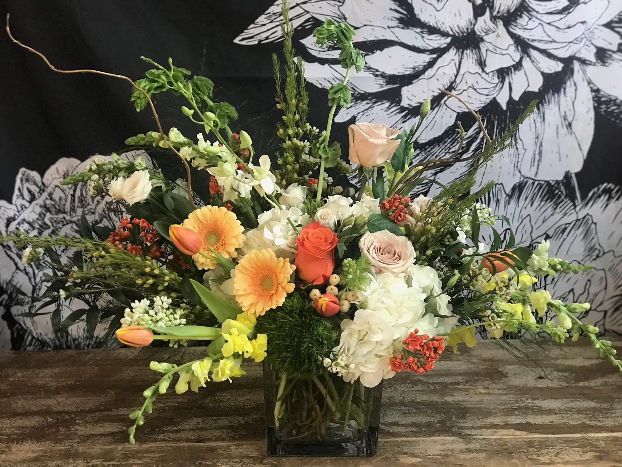Designer's Choice ~ Medium - A medium height floral arrangement in either glass or metal makes a great gift for any occasion. Our designer's choice arrangements are created with seasonal blooms and always with a unique twist. The photos shown are for reference- colors of flowers will vary but if you have a preference please specify in the notes section. 