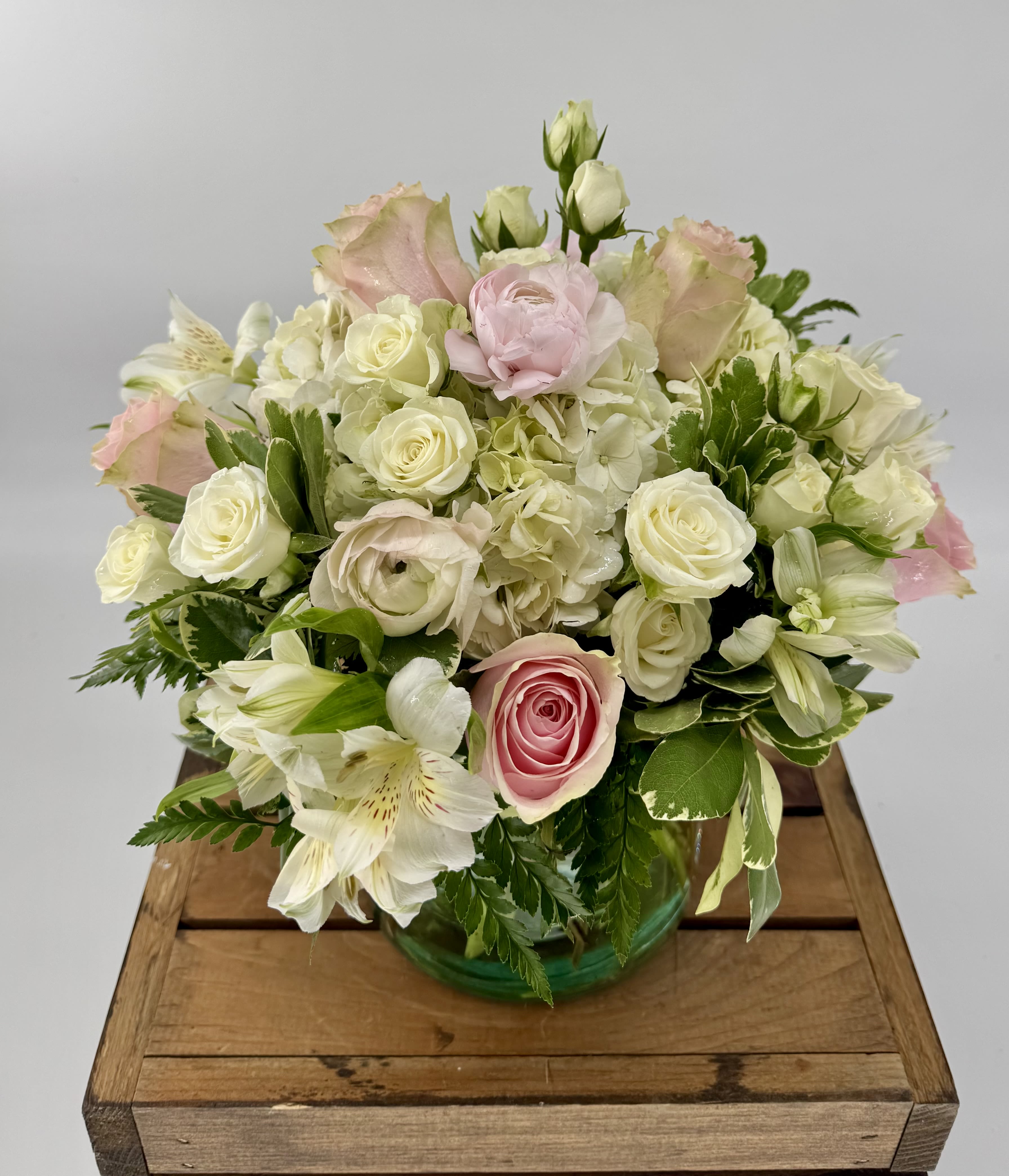 Happy Thoughts (BR) - Introducing our Happy Thoughts floral arrangement, a vibrant display of pinks and whites that will add a touch of elegance to any space. This exquisite arrangement features a perfect blend of hydrangea, pink ranunculus, pink roses, white spray roses, alstroemeria, and assorted greenery, expertly crafted in a sleek glass cylinder vase. 