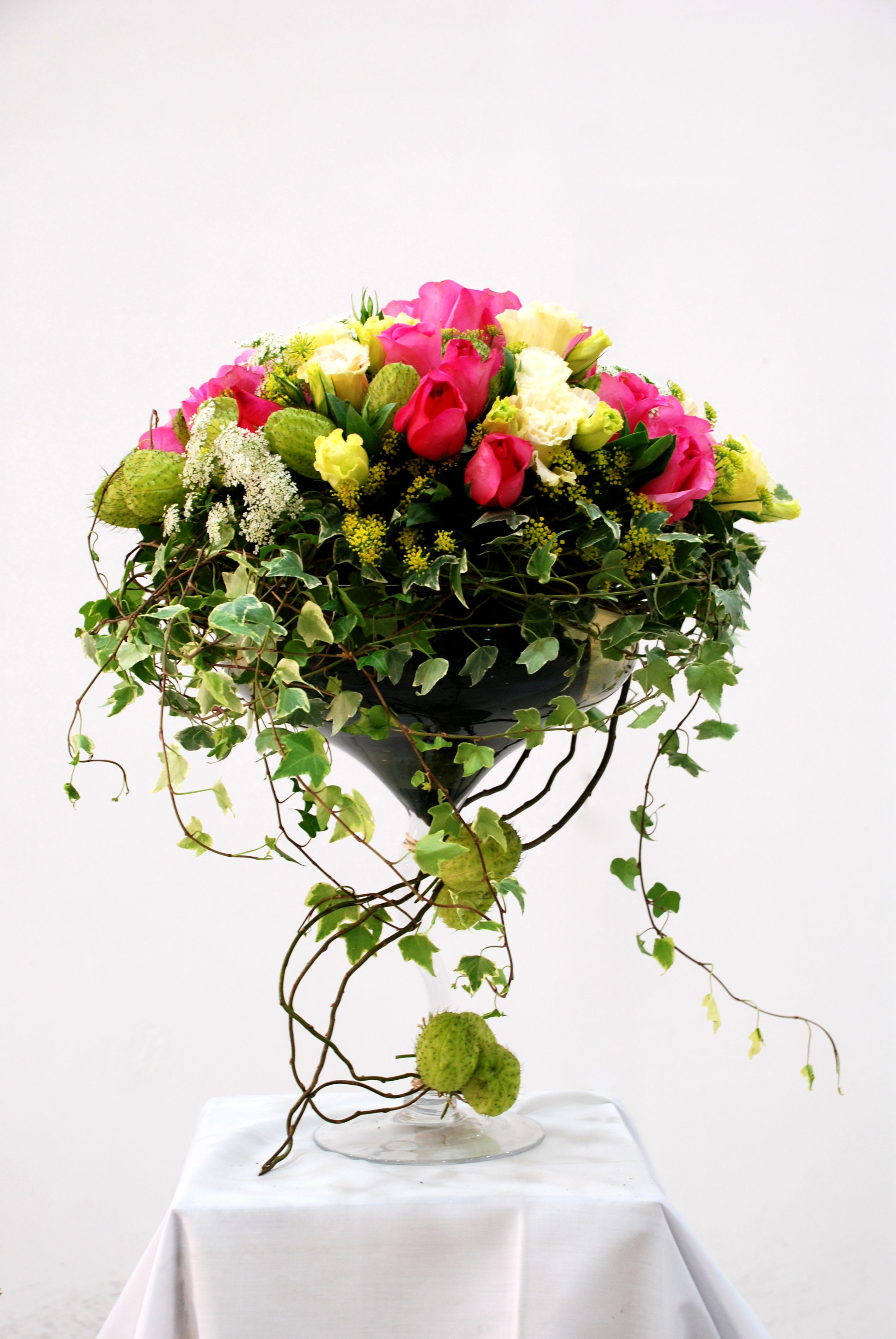 Ivy en Fleur - A sculptural celebration of nature’s elegance, [Name] is a luxurious composition of vivid pink tulips, creamy roses, and trailing ivy, cradled in a dramatic vessel wrapped with winding vines. This striking piece blurs the line between floral art and garden fantasy—perfect for grand entrances, wedding pedestals, or gallery-style interiors. Each arrangement is a living sculpture, embodying the opulence and romance of European garden design with modern flair.