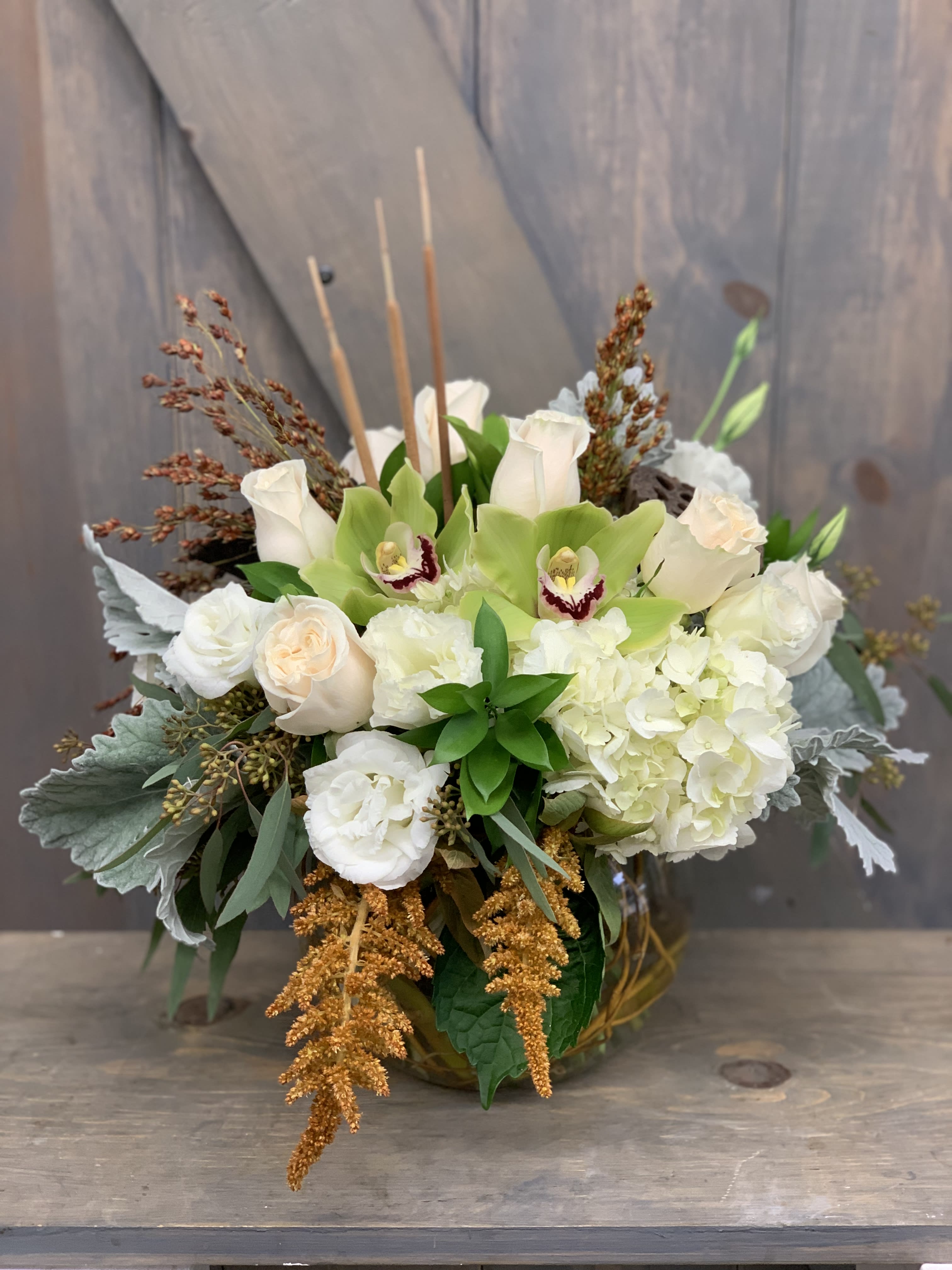 Autumn Elegance - This textural and calming arrangment has Roses, Cymbidium Orchids, Hydrangea, Lisianthus, Dusty Miller, Golden Amaranthus, Seeded Eucalyptus, Broom Corn, dried Lotus pods, and Cattails