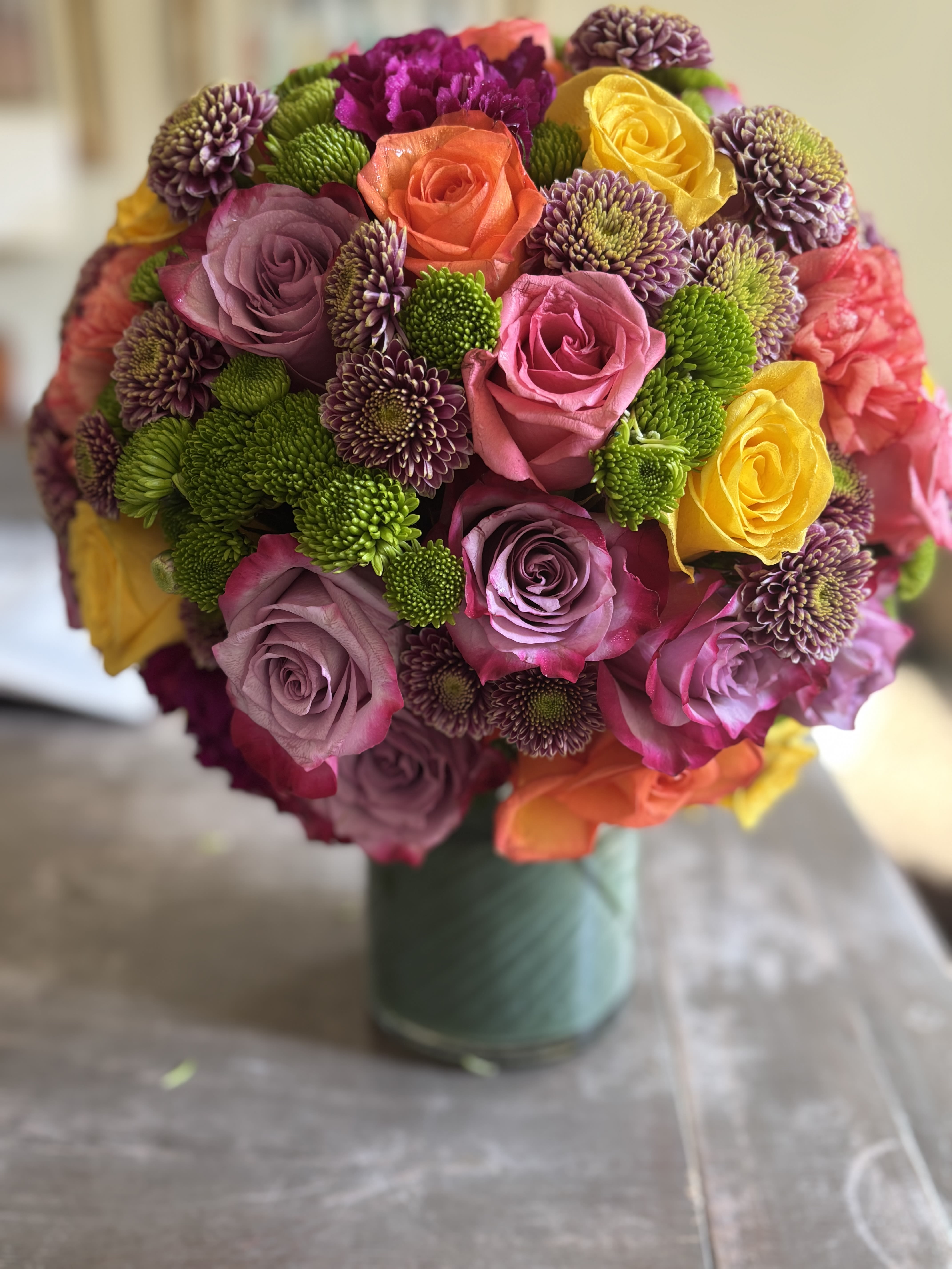 Ann - Beautiful bright roses , green hydrangeas, carnations and spray roses along with any seasonal florals arranged in a perfect round shape. 
