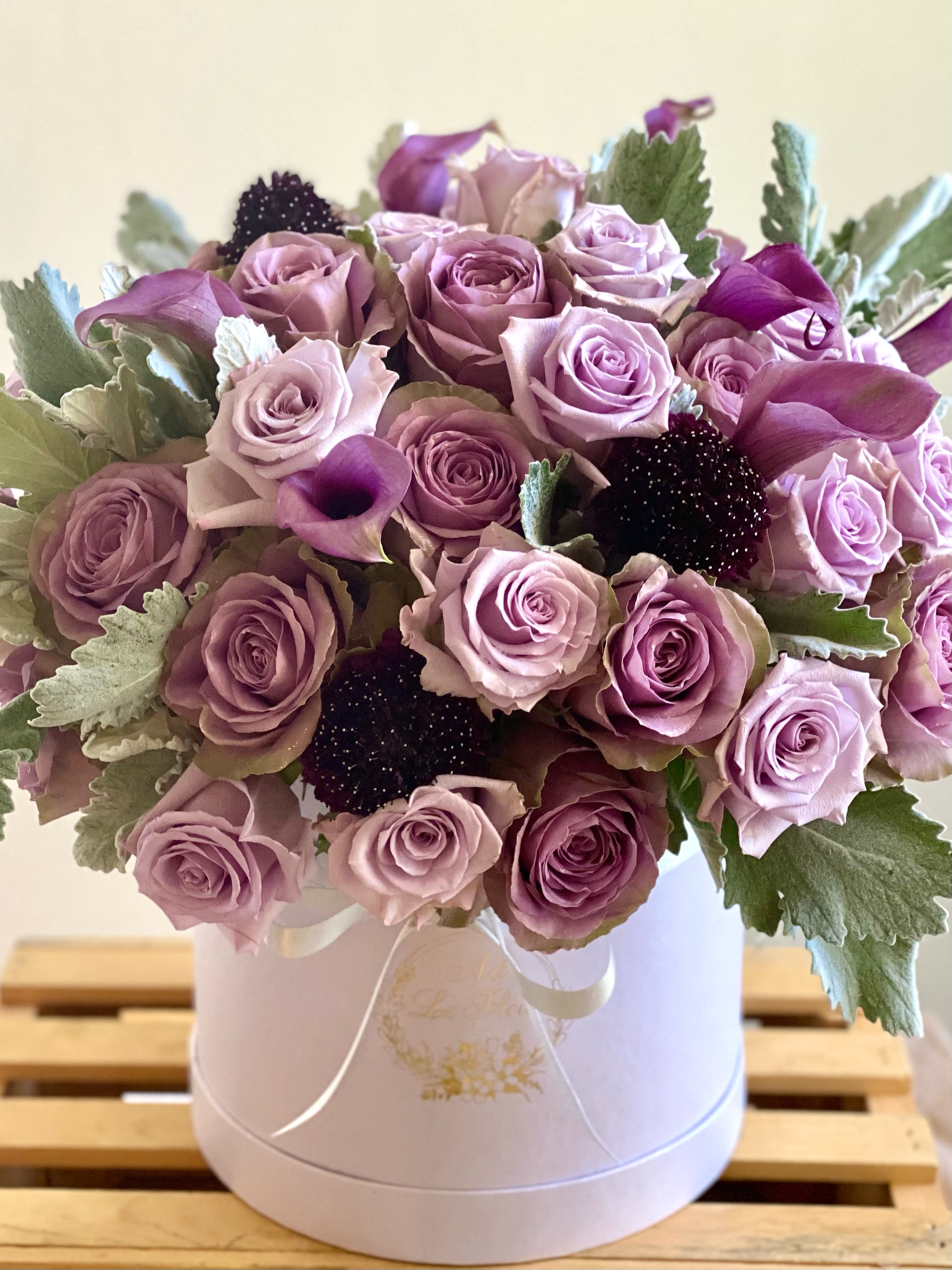 Elegance Box Elegance Box - Containing a minimum of 50 roses of unique varieties carefully chosen to fit into this creation that communicates elegance all around. The velvety touch of the silvery dusty miller leaves along with the striking deep purple scabious brings your senses to a new dimension of flowers. Perfect for a special occasion such as Thank you, love or congratulations. The Box itself measures aprox 8.5" H x 8" W. Color of the box is white. Your personalized handwritten card is always free with your order at Art Le Fleur.