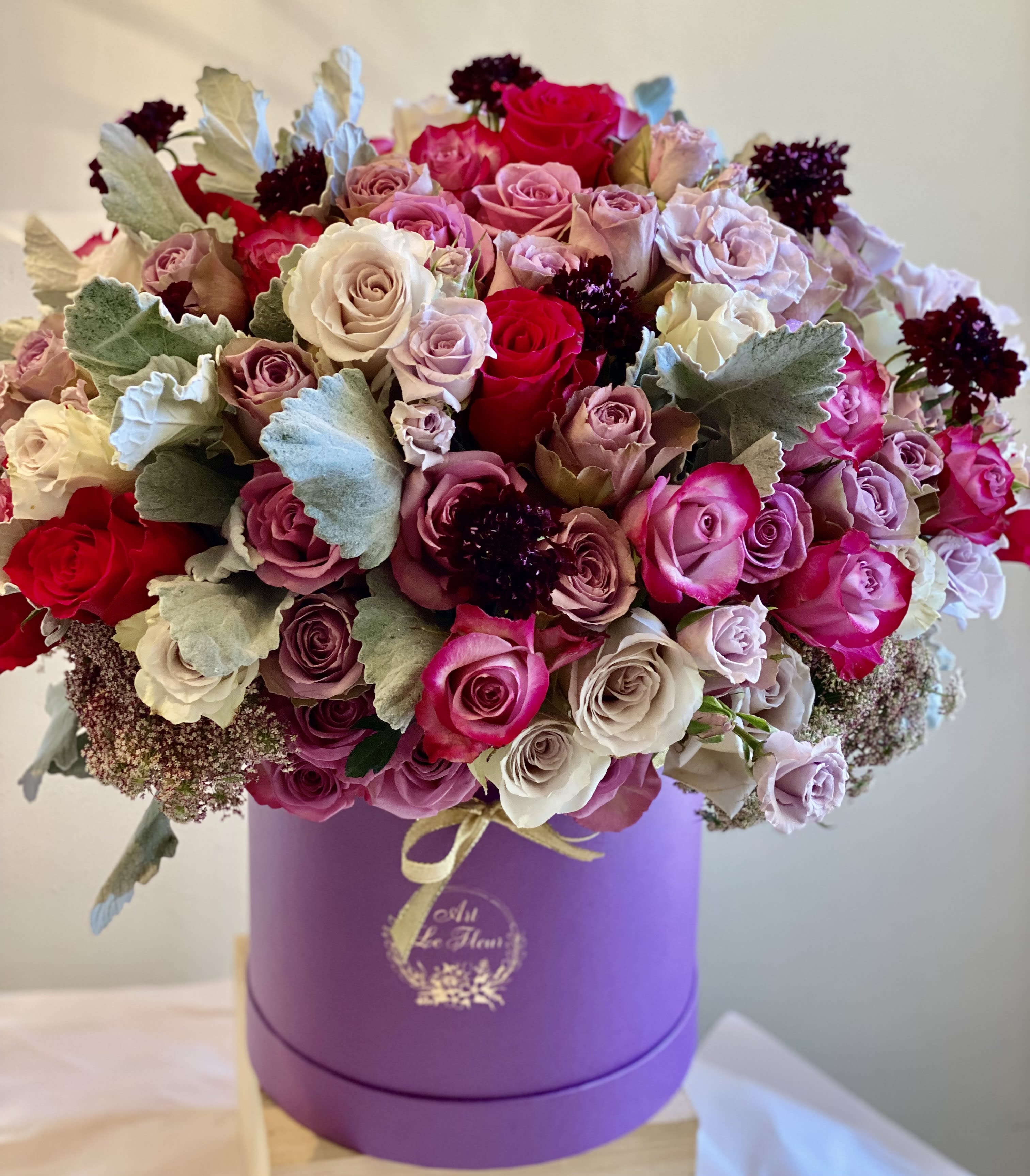 The Majestic! - This fresh design features a medley of about 100 roses, calla lilies, scabious, dusty miller, orchids and other textured elements. Pictured in shades of lavender and purple and accented with hot pink.  Perfect composition for an elevated impression, or acknowledgement. Our flowers are sourced daily per the order from our wholesalers. 