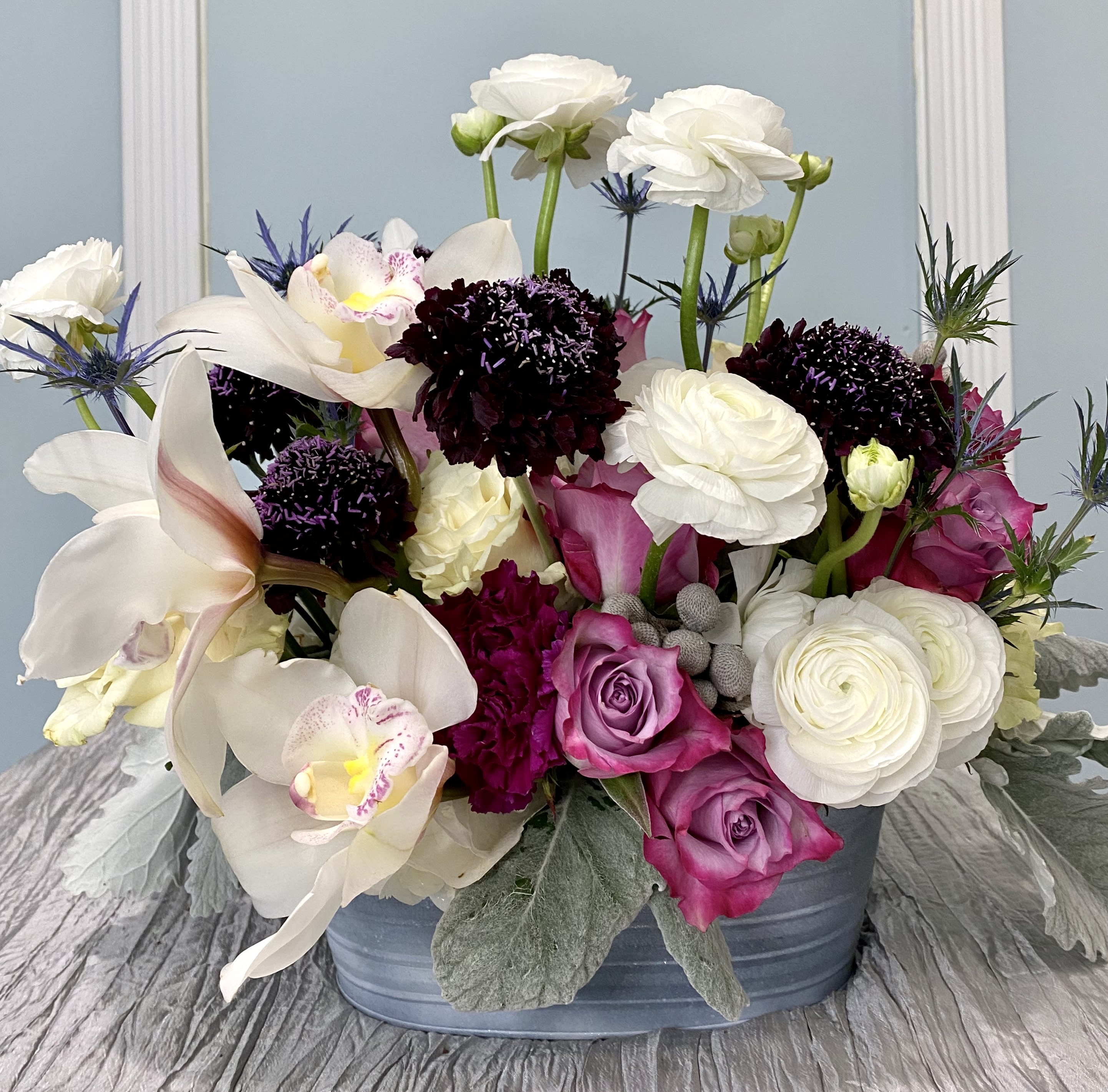 The Regal bouquet - A rich combination of whites, lavenders and purples. This splendid combination of delicate yet long-lasting and unique flowers promises to bring a WOW to any space it arrives. Textures from the silver bruwnia and dusty miller brings soft wintery look paired with the rich textured scabious.  The cymbidium orchid if not available will be replaced by a phalaenopsis orchid.  Your personalized card is always handwritten and always free with Art Le Fleur!