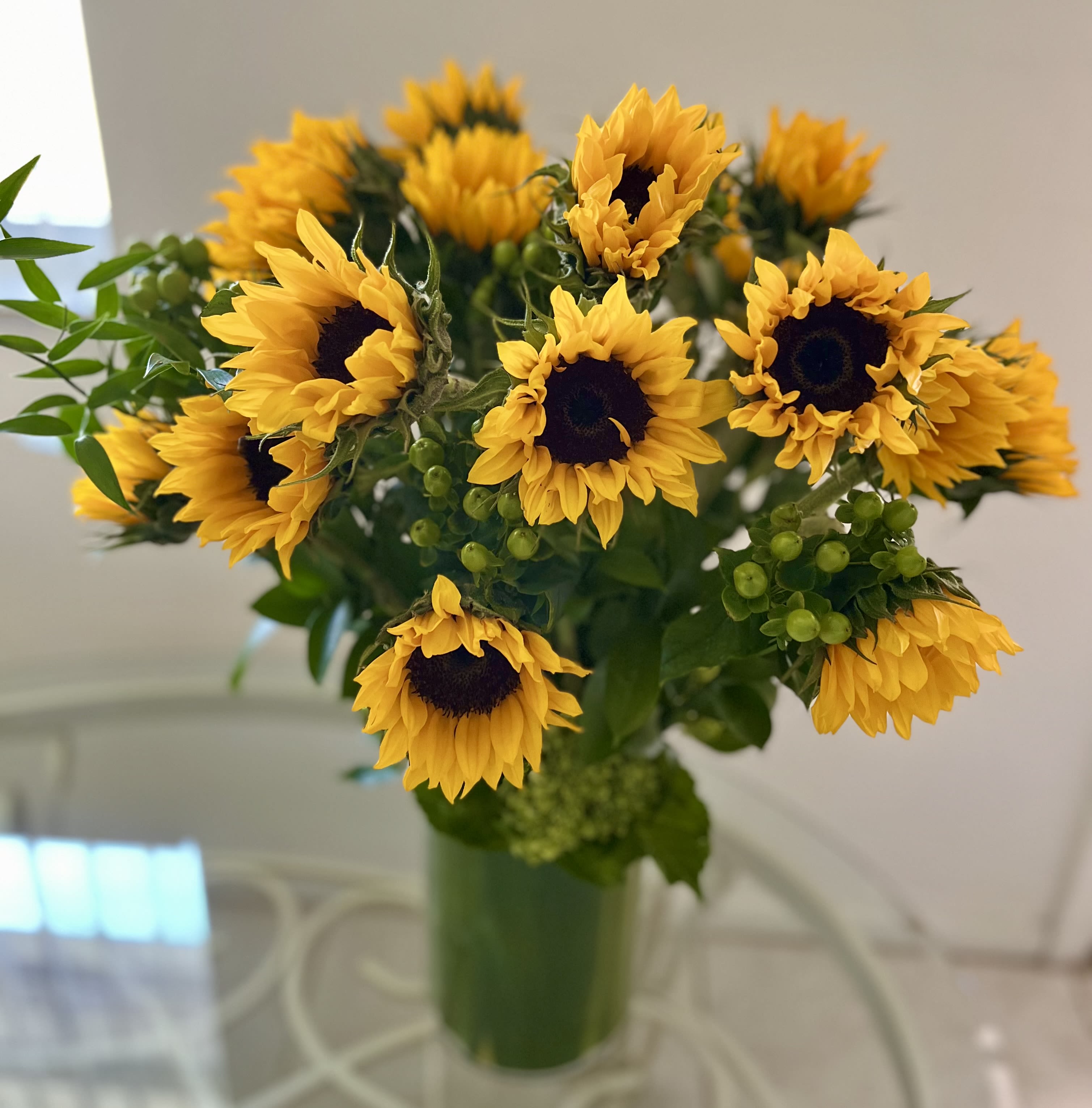 Sun & Flowers Sun & Flowers - Beautiful combination of sunflowers in a backdrop of green fillers such as hypericum, green hydrangeas, and greenery. Some seasonal touches might be added as the season progreses such as fall foliage.