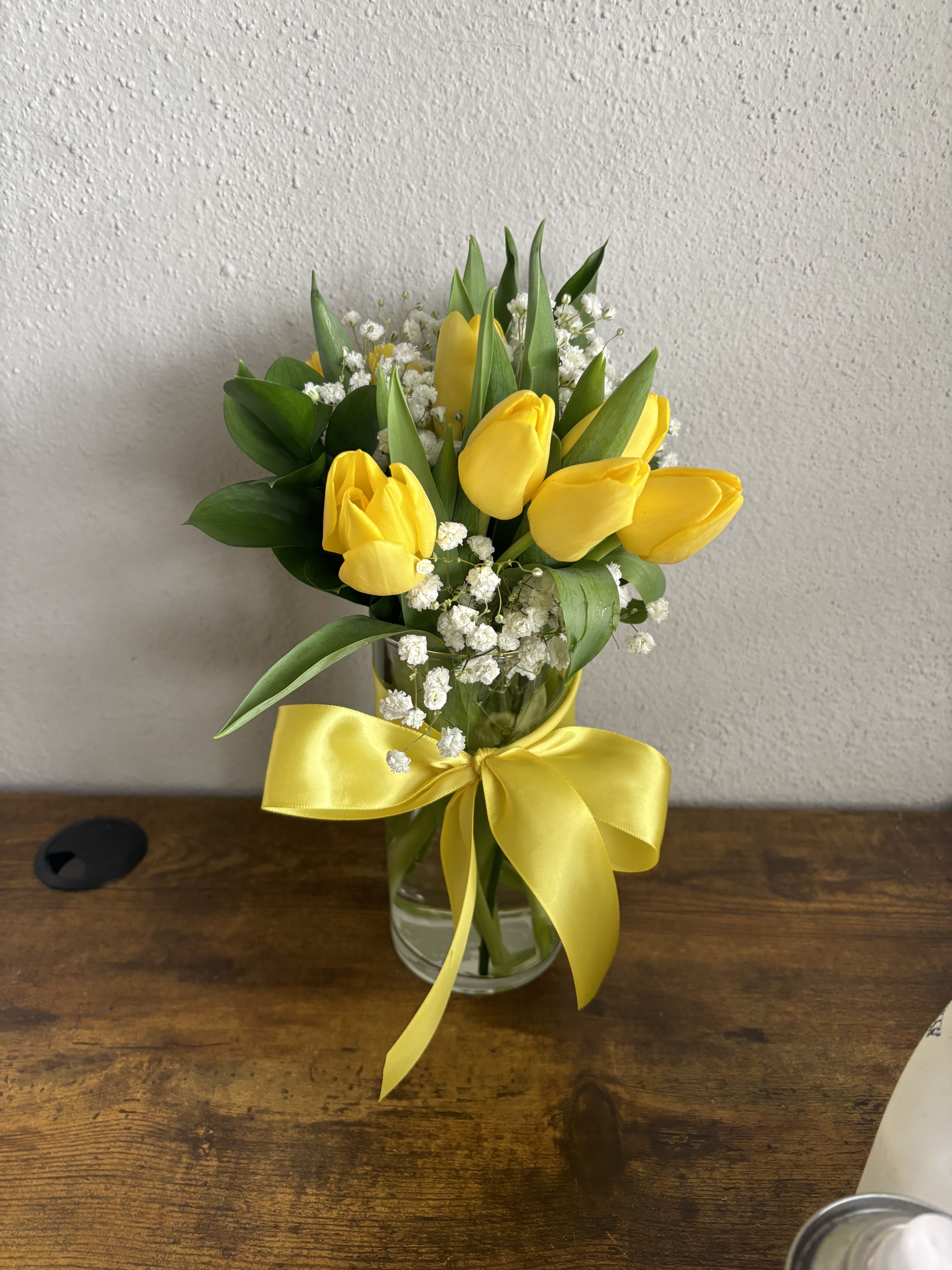 10 Tulipanes Amarillos en Vase - Un diseño fresco y sofisticado que combina la belleza natural de los tulipanes con la elegancia de un florero de cristal. Este arreglo de 10 tulipanes amarillos transmite alegría, optimismo y energía positiva, convirtiéndose en el regalo perfecto para cumpleaños, agradecimientos, nuevos comienzos o simplemente para iluminar cualquier espacio.  Cada tallo es seleccionado con cuidado para garantizar frescura y duración, creando un detalle que aporta luz y elegancia en todo momento. 