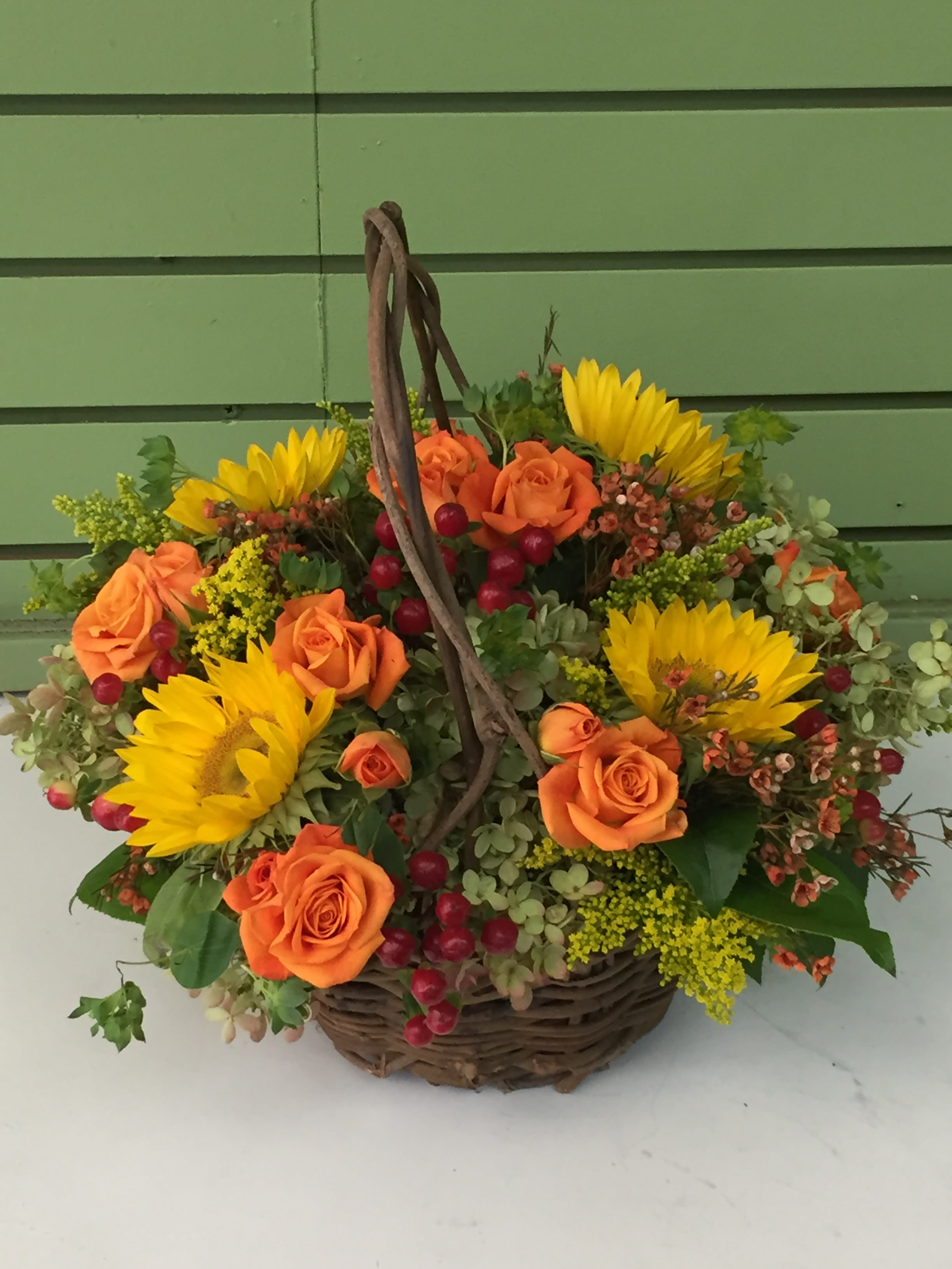 Fall Seasonal Centerpiece (Round) -  Assorted  blossoms in a homey wicker basket. Selection varies by season. Can also be designed in a glass dish for use as a dining centerpiece