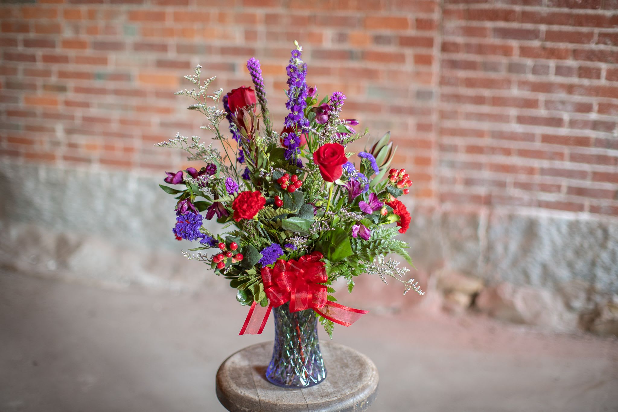 Amethyst and Ruby - In a brilliant cut lavender vase are jewel toned beauties. Rich roses, linear larkspur and liatris flowers are paired with bold alstroemeria. Royal purples and precious reds pair perfectly to make a bold statement. These gems are a beautiful combination for all occasions. 