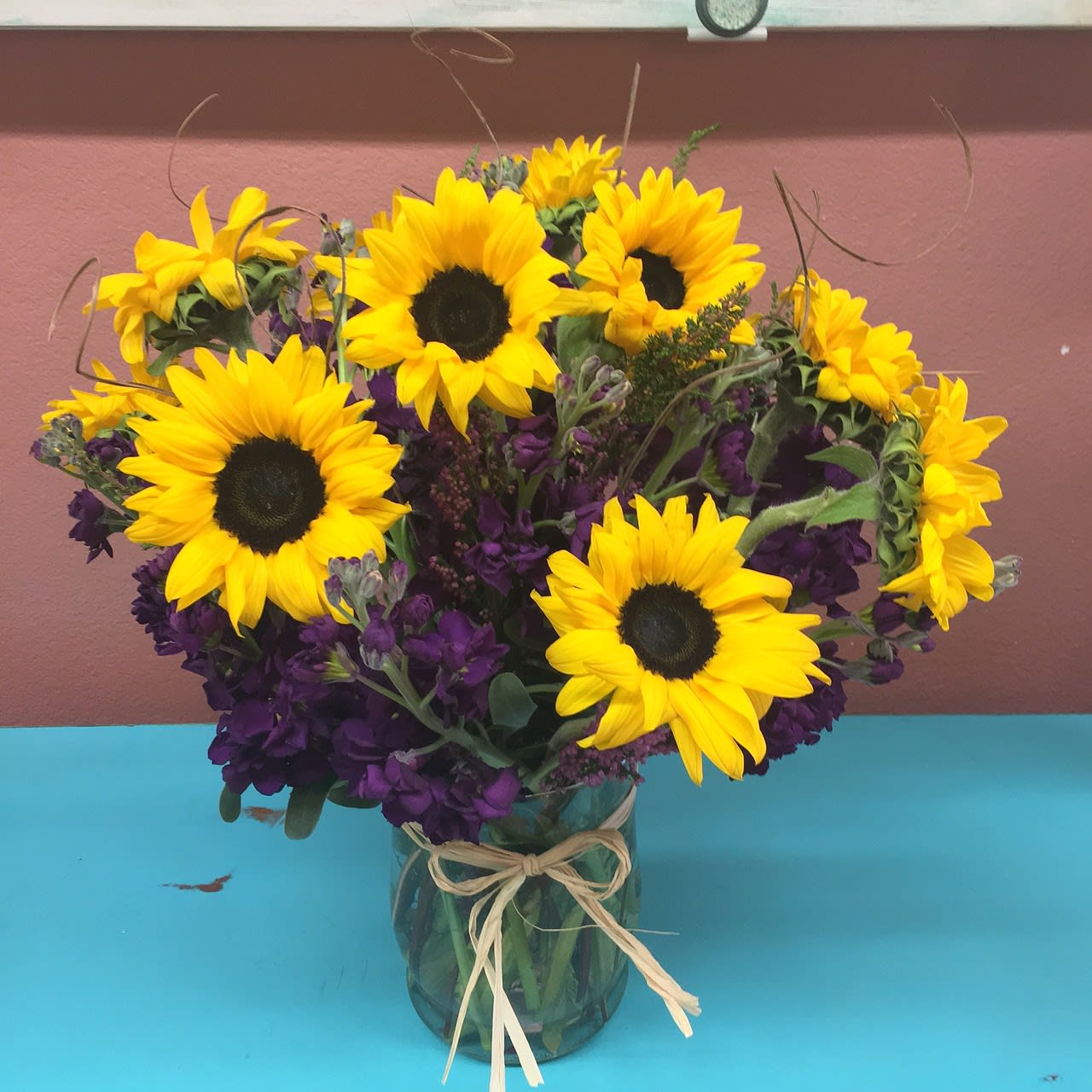 Rays of Sunshine - Show her how much she lights up your life with this beautifully, handcrafted arrangement of a Dozen Sunflowers, accented with fragrant Stock and ting ting. The vase is adorned with a bow.  Vase and color may vary. 