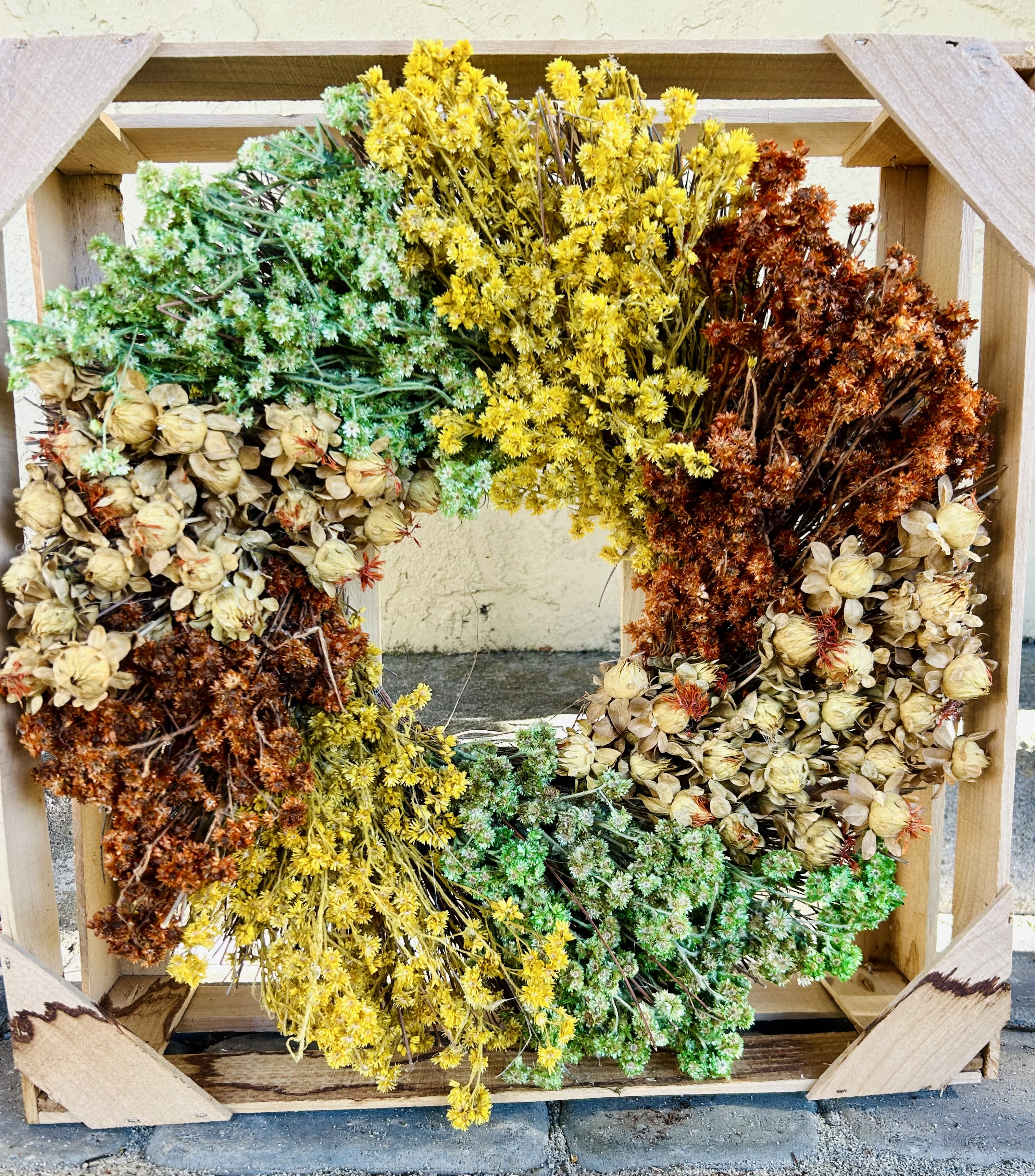 Autumn Dried Flower Wreath Autumn Dried Flower Wreath - Using mixed autumn colors and an arrangement of natural dried flowers, this beautiful hand-made wreath fits perfectly with any decor. -19” diameter -Each wreath comes in a wooden crate for storage and display