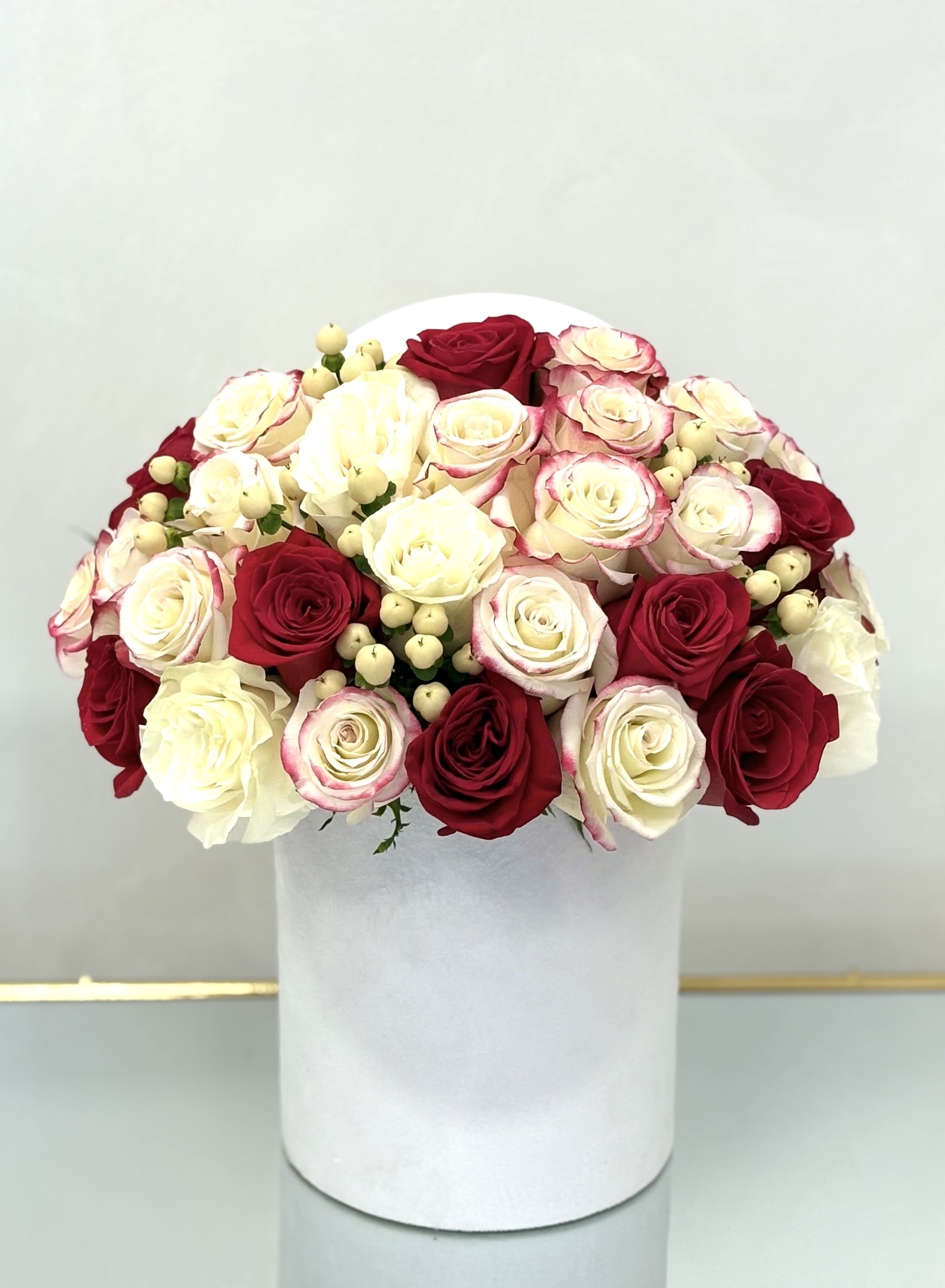 Elegancia By VLM Flowers - This graceful round box of rich crimson, snowy white, and bi-color roses brings classic romance into a modern form. Creamy berries add gentle texture and charm to this refined floral design.  Perfect For: Elegant home décor, stylish celebrations, or timeless love notes.