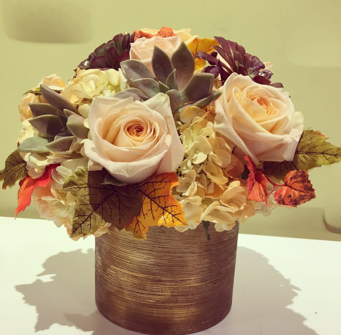 California Harvest  - A classic cylinder vase full of falls finest assortment; Peach roses, and Hydrangeas, that are complimented by a collection of succulents, and maple leaves.