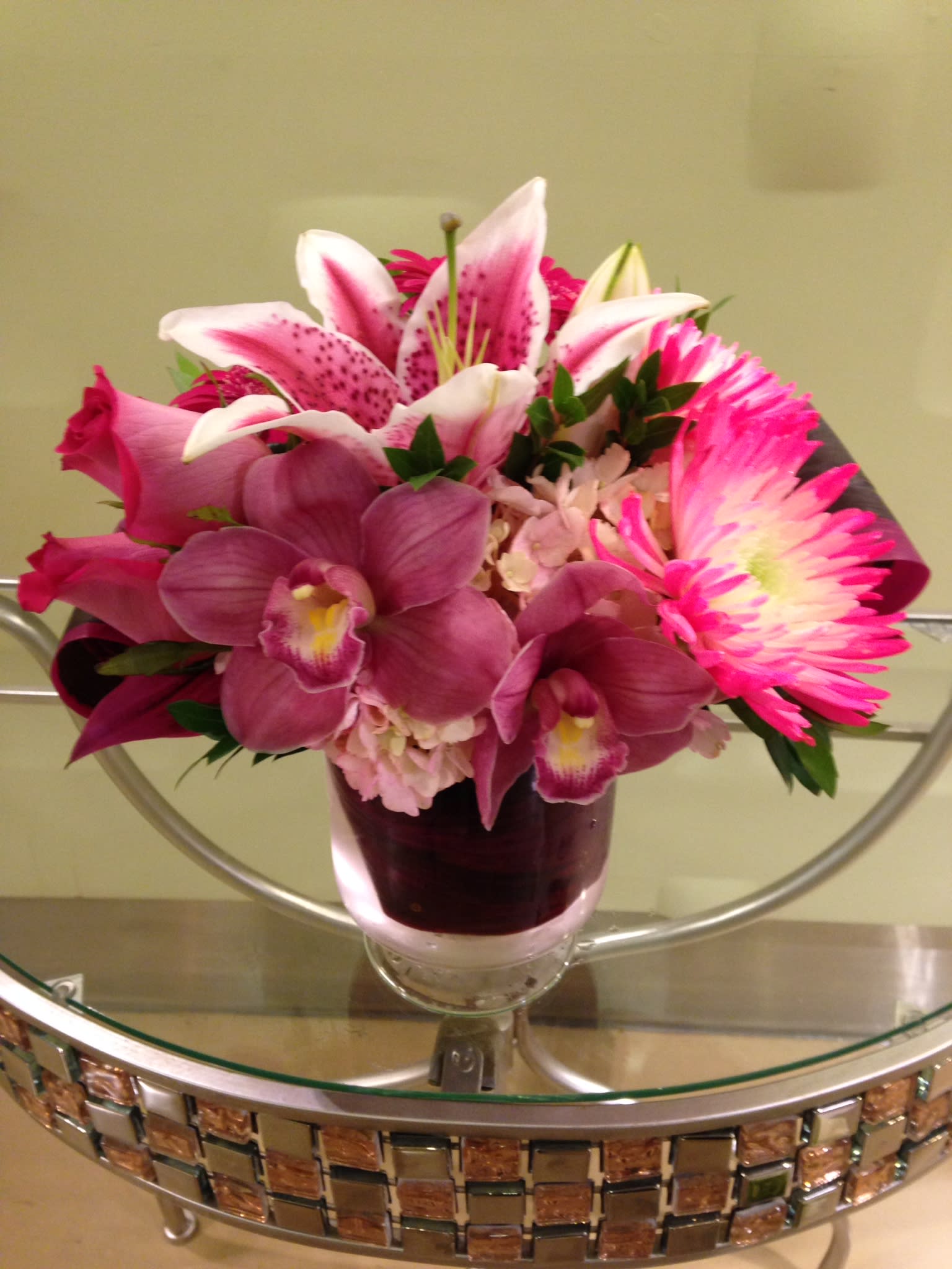 Keep me Blushing  - Keep me Blushing is fresh, its bright pink, and it has a little added exotic flare.  Featuring : gorgeous pink roses, pink stargazer lilies, pink spider mums &amp; cymbidium orchids. It all comes together in a round glass bowl with exposed green leaves wrapped along the inside.    