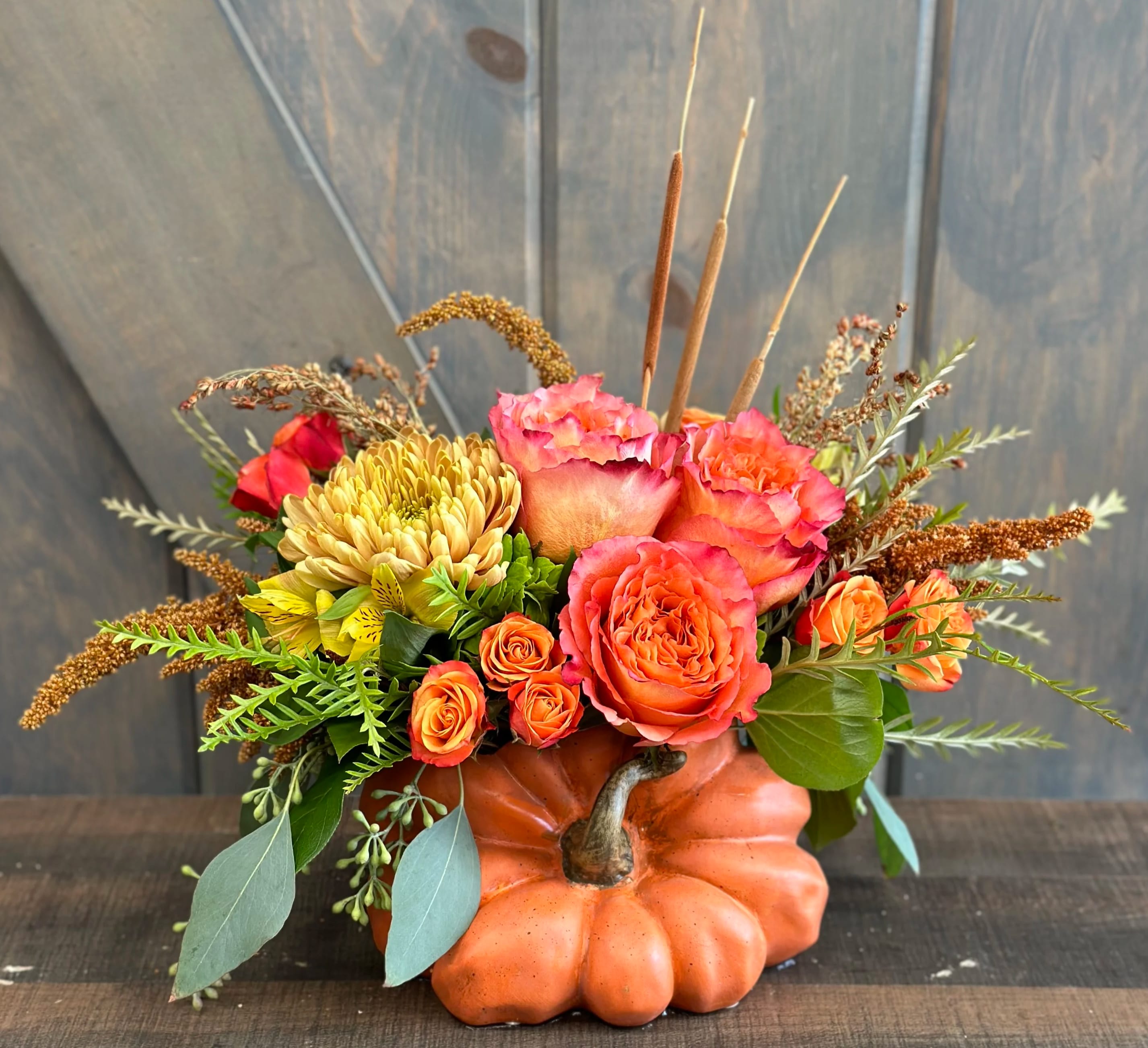 Pumpkin Spice - This arrangement come in a beautiful pumpkin ceramic container! The flowers included in this design are Roses, Spray roses, Chrysanthemums, Alstroemeria, Amaranthus, Broomcorn, Cat-tails, and seeded eucalyptus