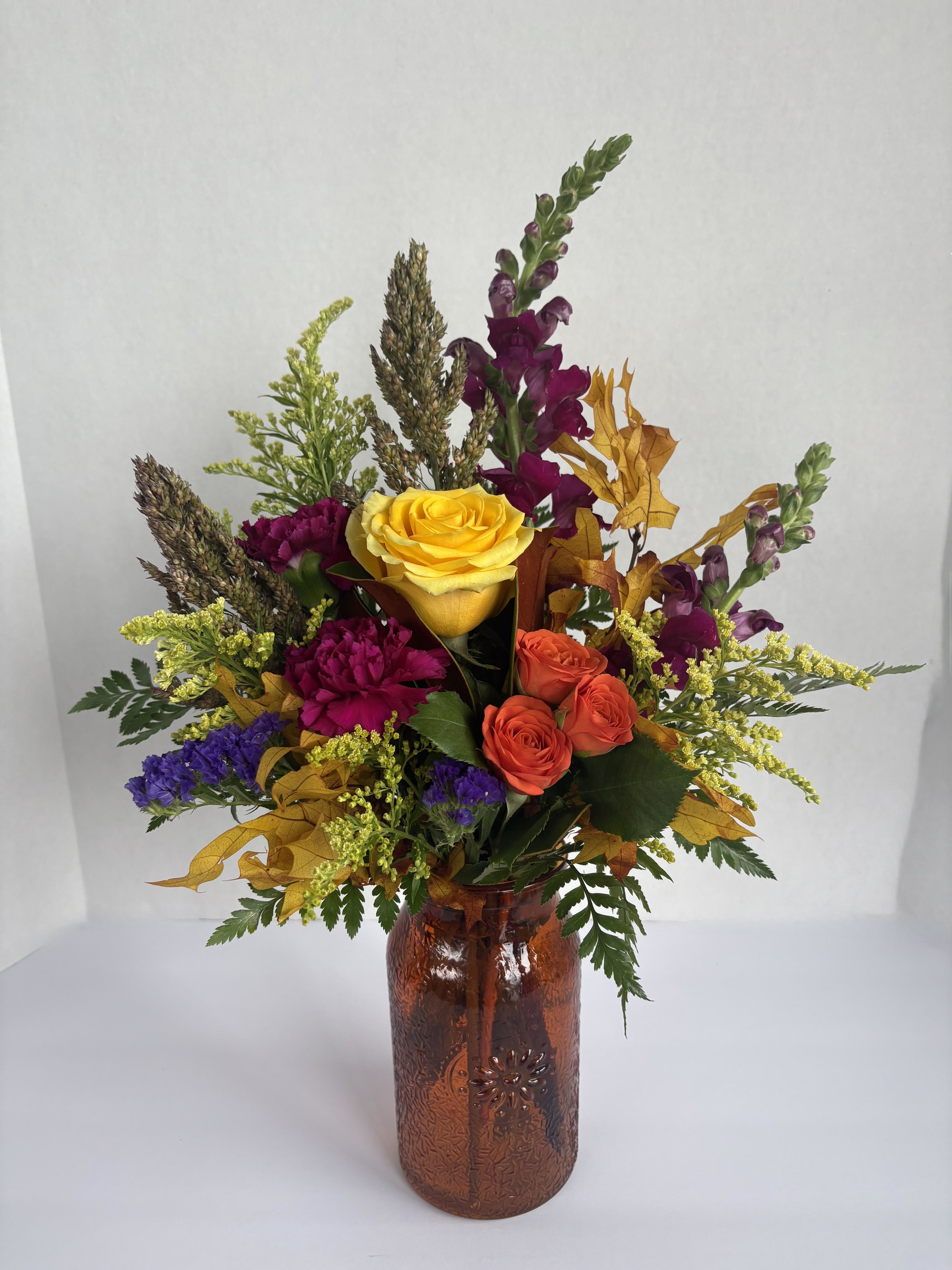 Fall Magic - Bring the magic of fall to life with this extraordinary arrangement.  A mixed bouquet with snapdragons, roses and carnations, brought together with fall leaves and a beautiful mix of fall foliage in a bright vase, this is certain to bring magic to anyone's day.