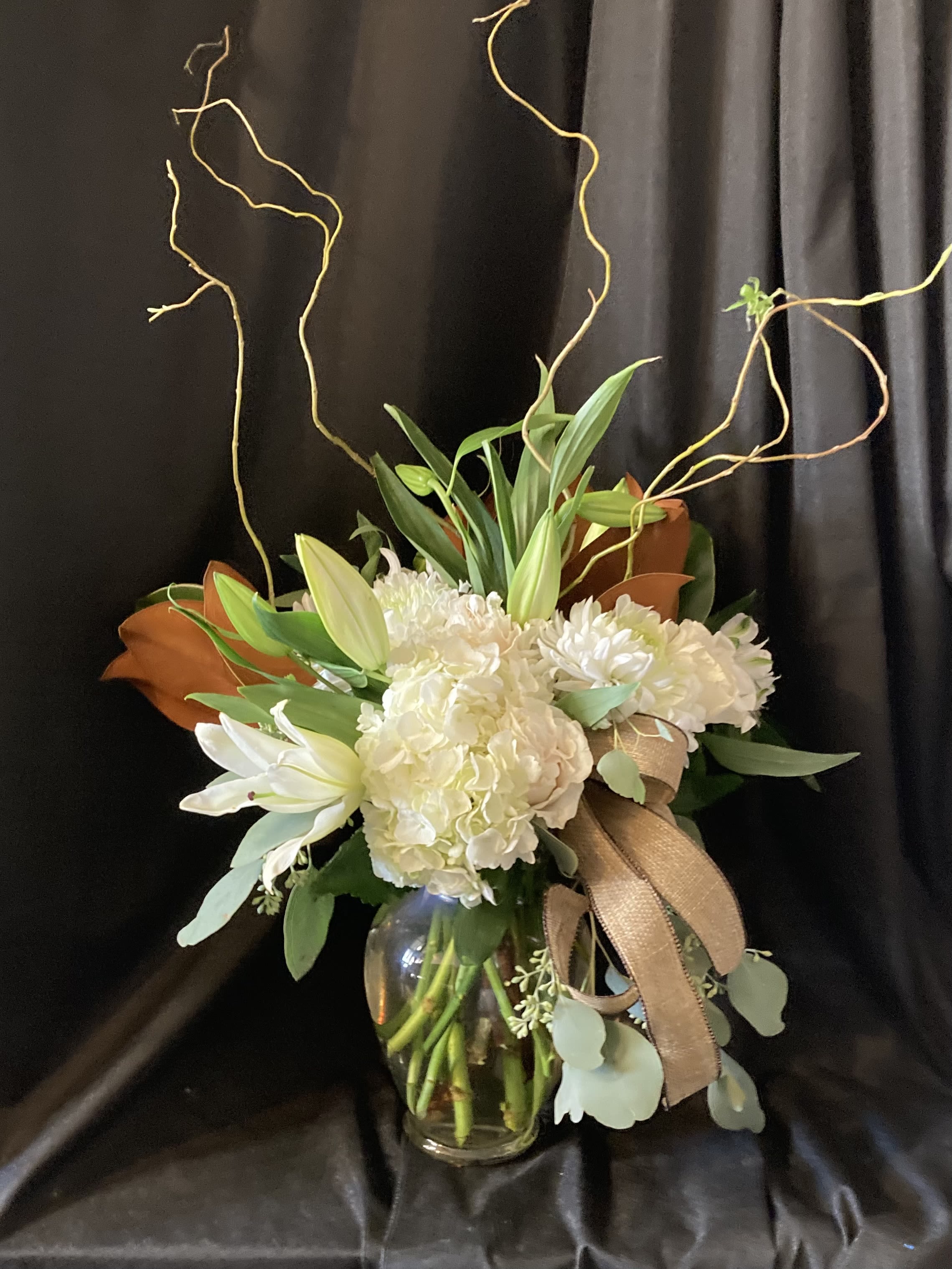 Magnolia Blooms - An all white arrangement set in magnolia blooms with seasonal blooms