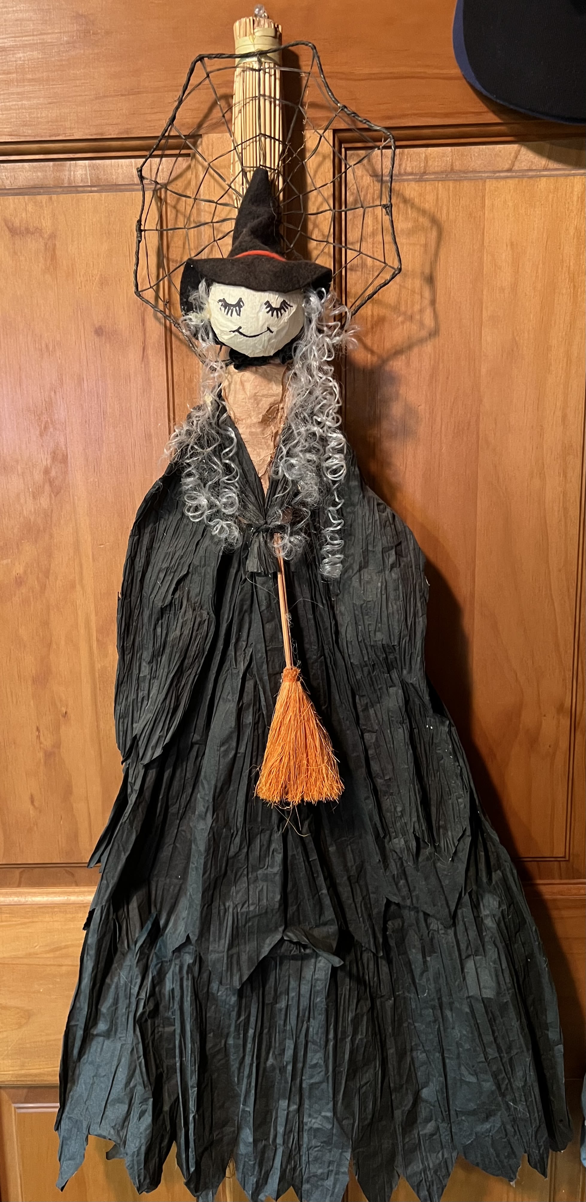 Witch Broom Door Decor - Our witch broom door decor is 35&quot; long. Indoor use only. Covered in black crepe paper attached to a broom. Holding an orange broom and ready to decorate your front door. Keep out of direct sunlight. Must be displayed indoor only.
