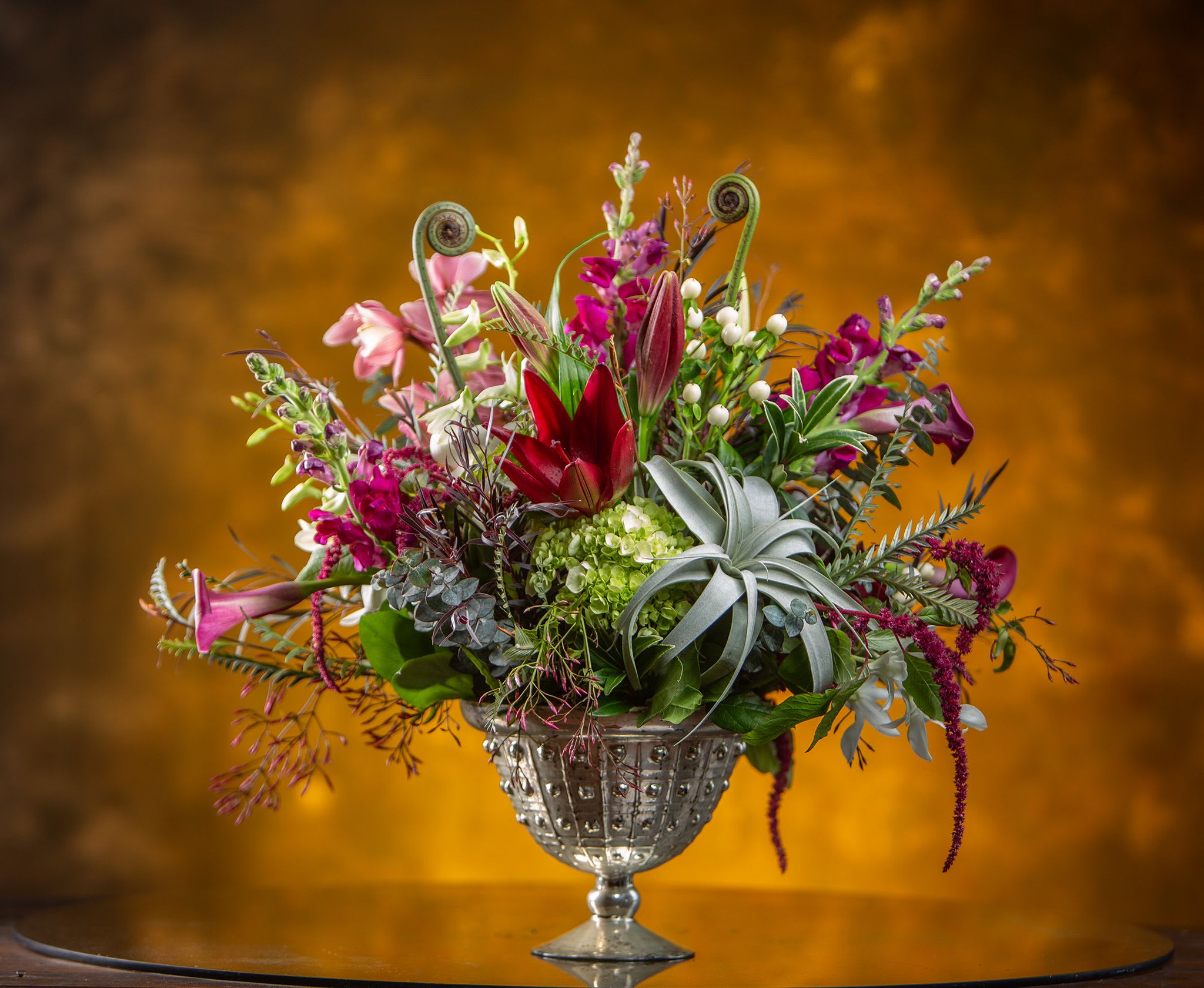 Enchanted Evening - A lovely way to add class and romance to a delightful event. This design comes in a mercury glass vase full of hydrangea, orchids, roses, and tillandsia. Spiced up with textural and whimsical berries, branches and pods. Select blossoms may change due to seasonal availability. Measures approximately 18&quot; by 24&quot; wide. Designed in a vase and delivered by us, a real Portland florist to anywhere in the greater Portland Oregon area. Place your order online, or call us directly 503 223 1646