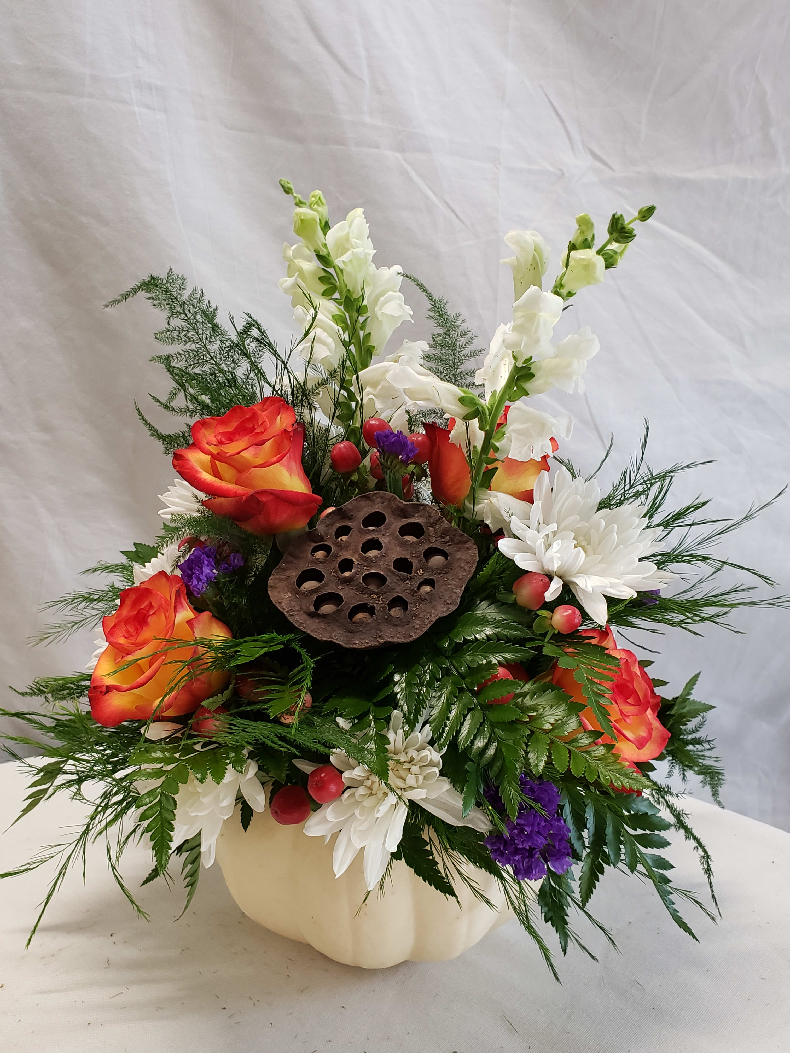 Modern Pumpkin Traditional Arrangement - A modern white pumpkin bursting with gorgeous roses (color may vary on availability), lotus pods, white chrysanthemums, and greens,