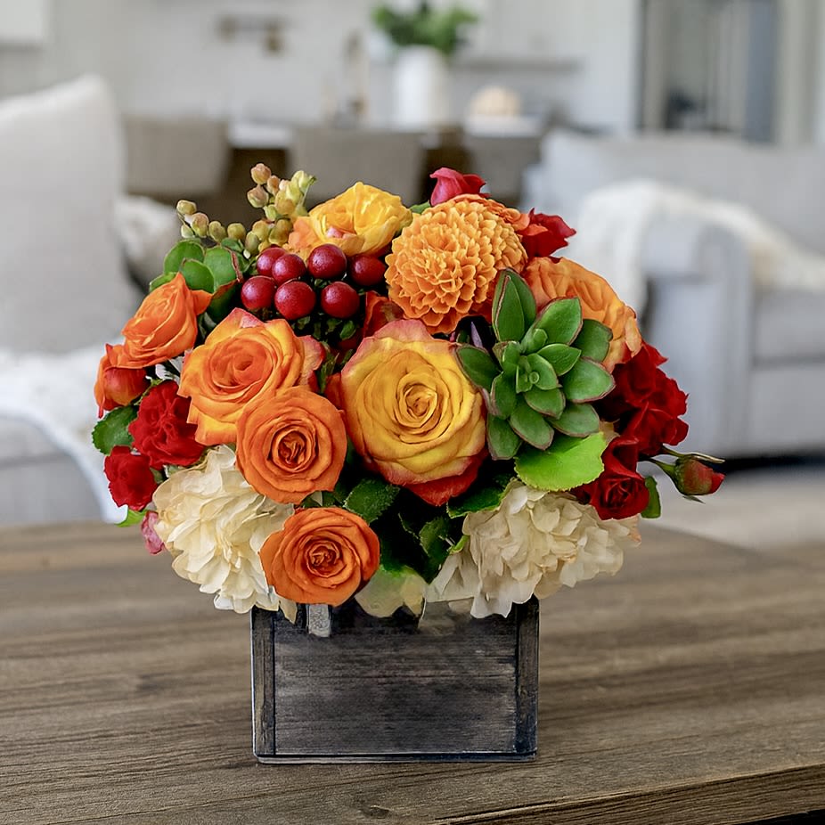 Tuscany Sunset - Seasonal Fall Arrangement - Tuscany Sunset Arrangement – Rustic Fall Floral Design  Bring the warmth of autumn into any home with our Tuscany Sunset Arrangement, a rustic floral design inspired by the glowing colors of a Tuscan sunset. This handcrafted centerpiece features a radiant mix of orange roses, vibrant spray roses, lush hydrangeas, orange mums, succulents, and hypericum coffee bean, all beautifully arranged in a rustic wooden box.  Perfect for the fall season, this cozy floral display makes a heartfelt gift for family, friends, or anyone who deserves a thoughtful surprise. Not only does it brighten up any space with rich seasonal tones, but the succulents can also be replanted, offering a lasting touch of greenery.  Whether you’re sending a “just because” bouquet, a fall gift, or a warm expression of appreciation, the Tuscany Sunset Arrangement is a cheerful reminder of nature’s beauty—perfect for celebrating autumn in style.