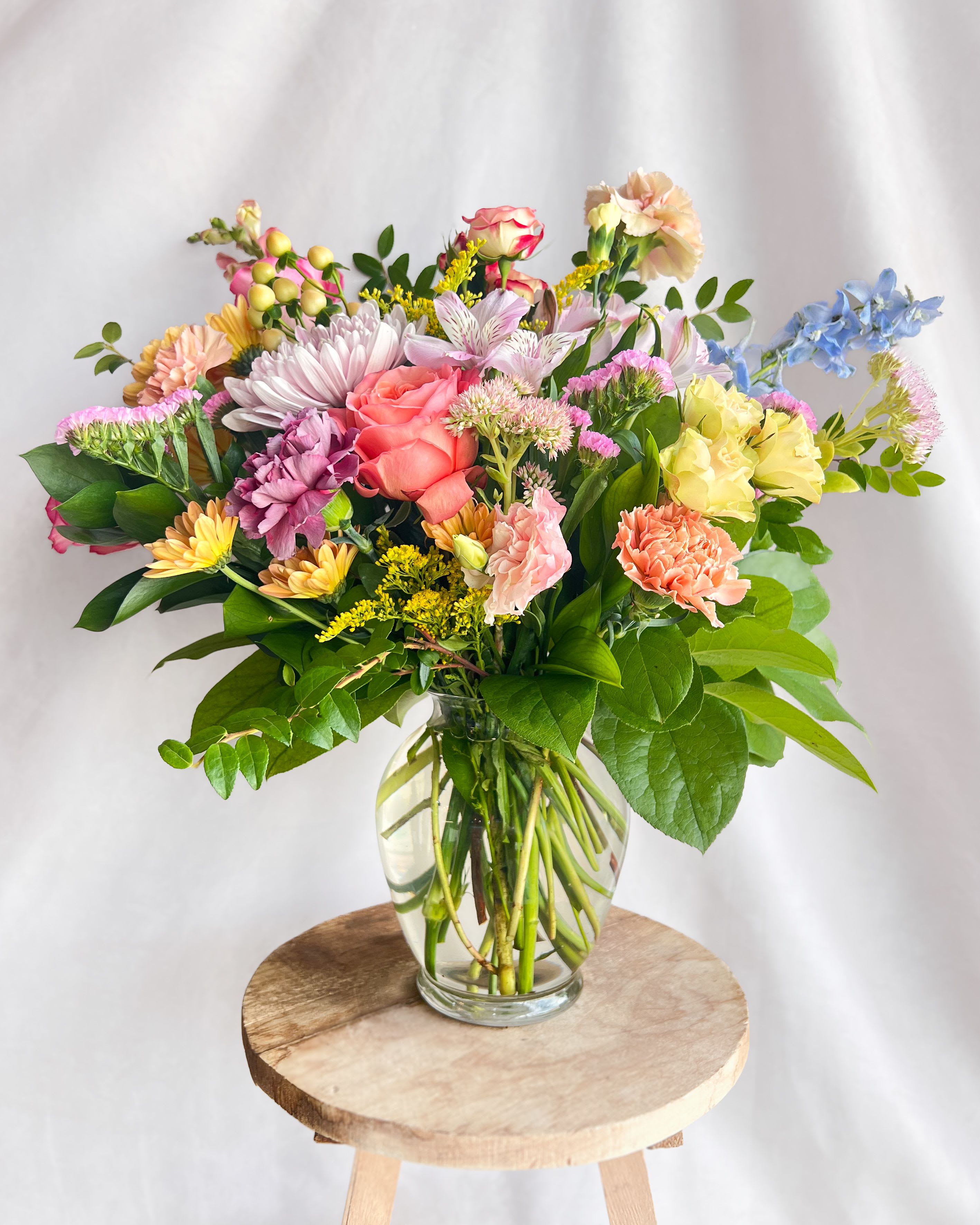 Spring Surprise - Farm fresh flowers in glass vase giving that just picked vibe. Product is subject to change based on seasonal availability. Picture for style reference &amp; size.  We prioritize delivering high-quality designs that are also cost-effective. To achieve this, we collaborate with a farm in Stillwater, OK, and use locally sourced flowers that are in season. PLEASE NOTE THE DESIGNS WILL DIFFER from the images depicted, but our commitment to delivering superior quality designs at an affordable price remains constant. 