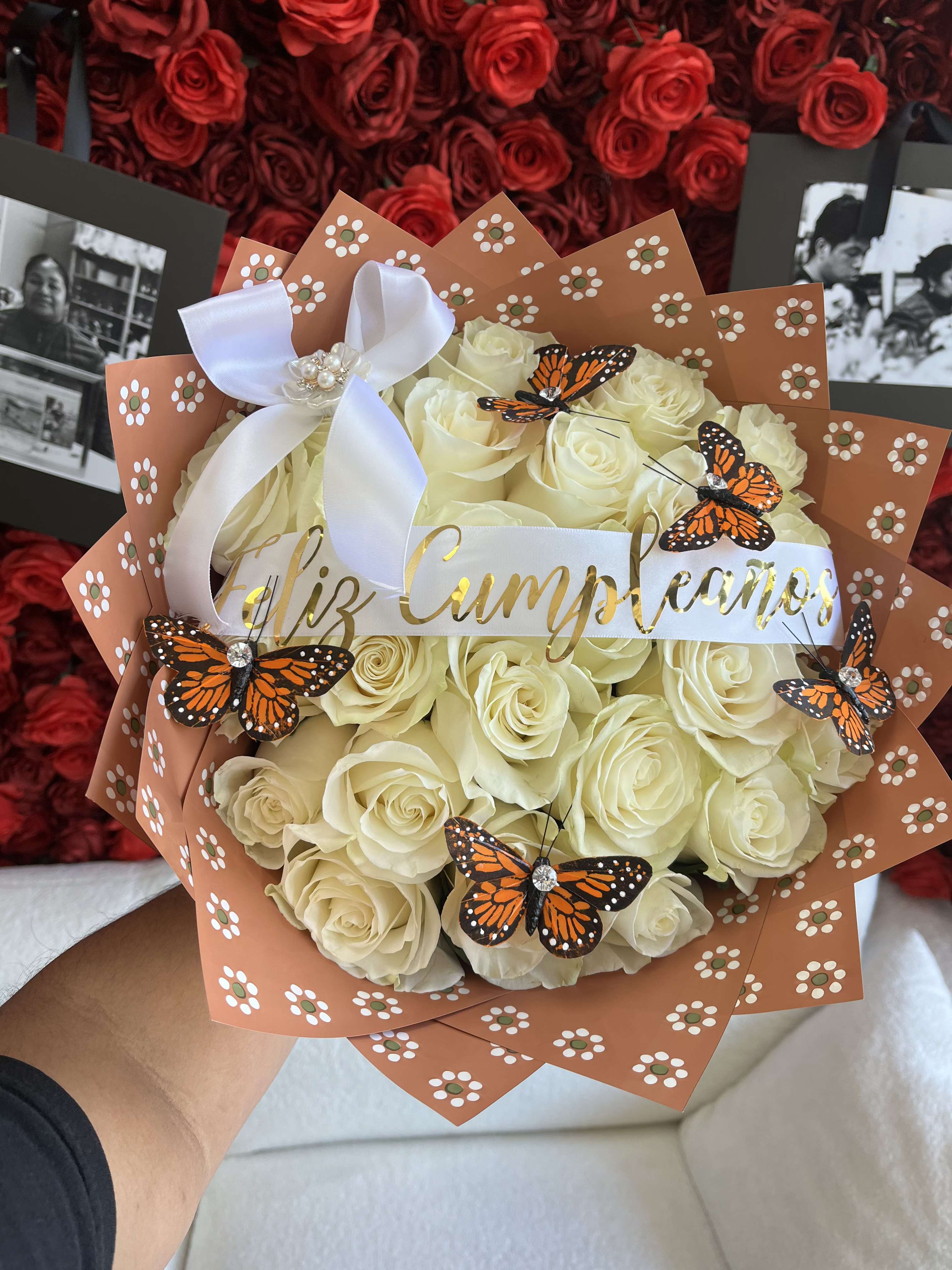 Monarch Bqt - A stunning bouquet of pristine white roses wrapped in a warm clay-brown wrap for a natural, rustic touch. Adorned with delicate monarch butterflies and thoughtfully accented with blooms on the corners. Complete with a personal message.  Note: PICTURED IS THE STANDARD SIZE.  **Please add the following in Special Instructions: ** 1.Personalized Message on Banner