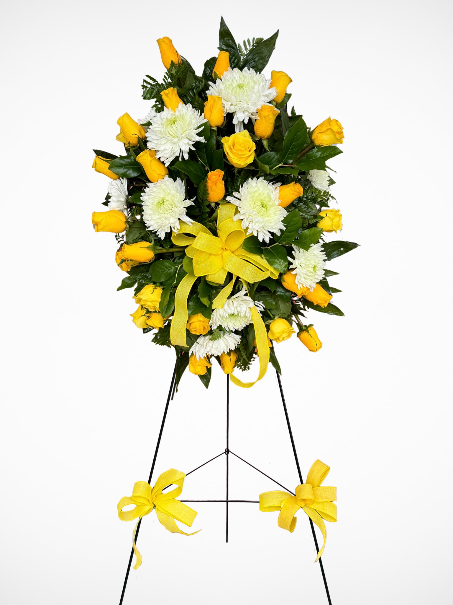 Golden Tribute Standing Spray - This standing spray is a graceful expression of love, remembrance, and hope. Featuring bright yellow roses paired with elegant white mums, it creates a striking balance of warmth and serenity. Finished with lush greenery and accented with a cheerful yellow bow, this spray is a meaningful way to honor a loved one and bring comfort during a time of loss.