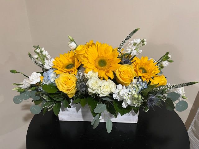 SPECTACULAR SUNRISE - (PREMIUM Shown) Low and Long Rectangular Whitewashed Wooden Box Arrangement Measuring: 3 ½” H x 11 ¼” L x 4” W, filled with White and Blue Hydrangea, Sunflowers, Yellow Roses, White Clustered Roses. White Stock, Loosestrife, Starfish Ornament, Premium Filler Flowers and Greens