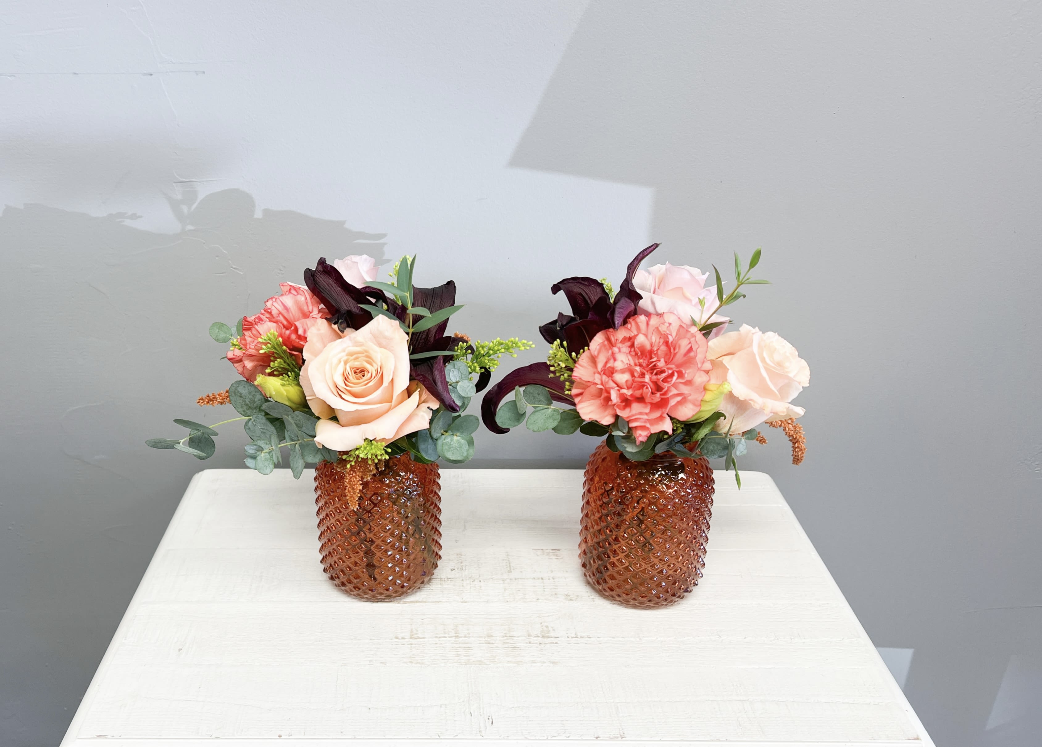Autumn Glow Luxe Collection  - Autumn Glow Luxe Collection Bring warmth and elegance into any space with our Autumn Glow Luxe arrangements. Featuring premium lilies, lush roses, carnations, and seasonal textures in a chic amber glass vase, this collection offers timeless charm. 	•	Duo (2 arrangements) – $100 	•	Trio (3 arrangements) – $135 	•	Quartet (4 arrangements) – $225   Perfect for weddings, events, or creating a coordinated seasonal look throughout your home or office.  