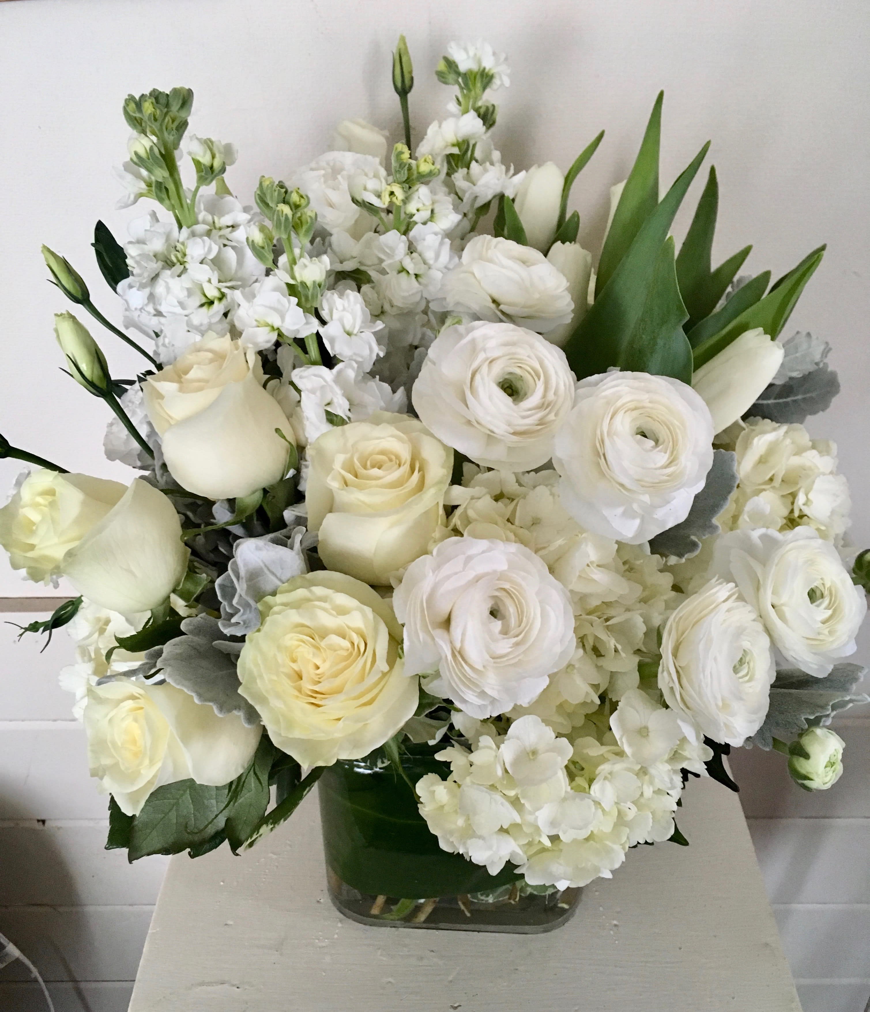 WHITE WHISPERS - GLASS CONTAINER FILLED WITH WHITE LISIANTHUS, WHITE ROSES, WHITE TULIPS, WHITE STOCK, WHITE HYDRANGEA AND DUSTY MILLER