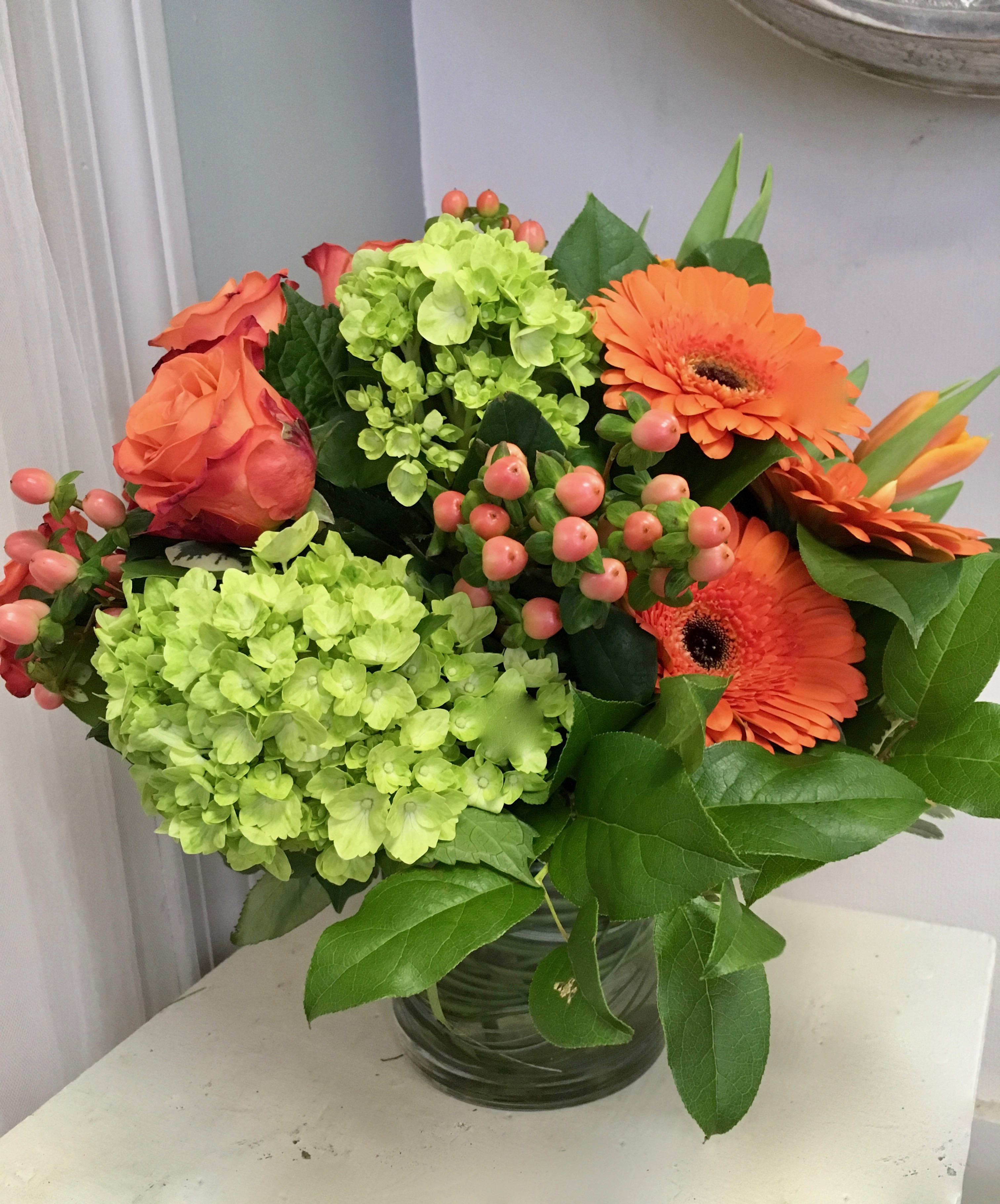 Orange  Delight - Glass vase filled with orange gerbera daisy's, green hydrangea, orange roses, orange tulips and orange hypericum berries 