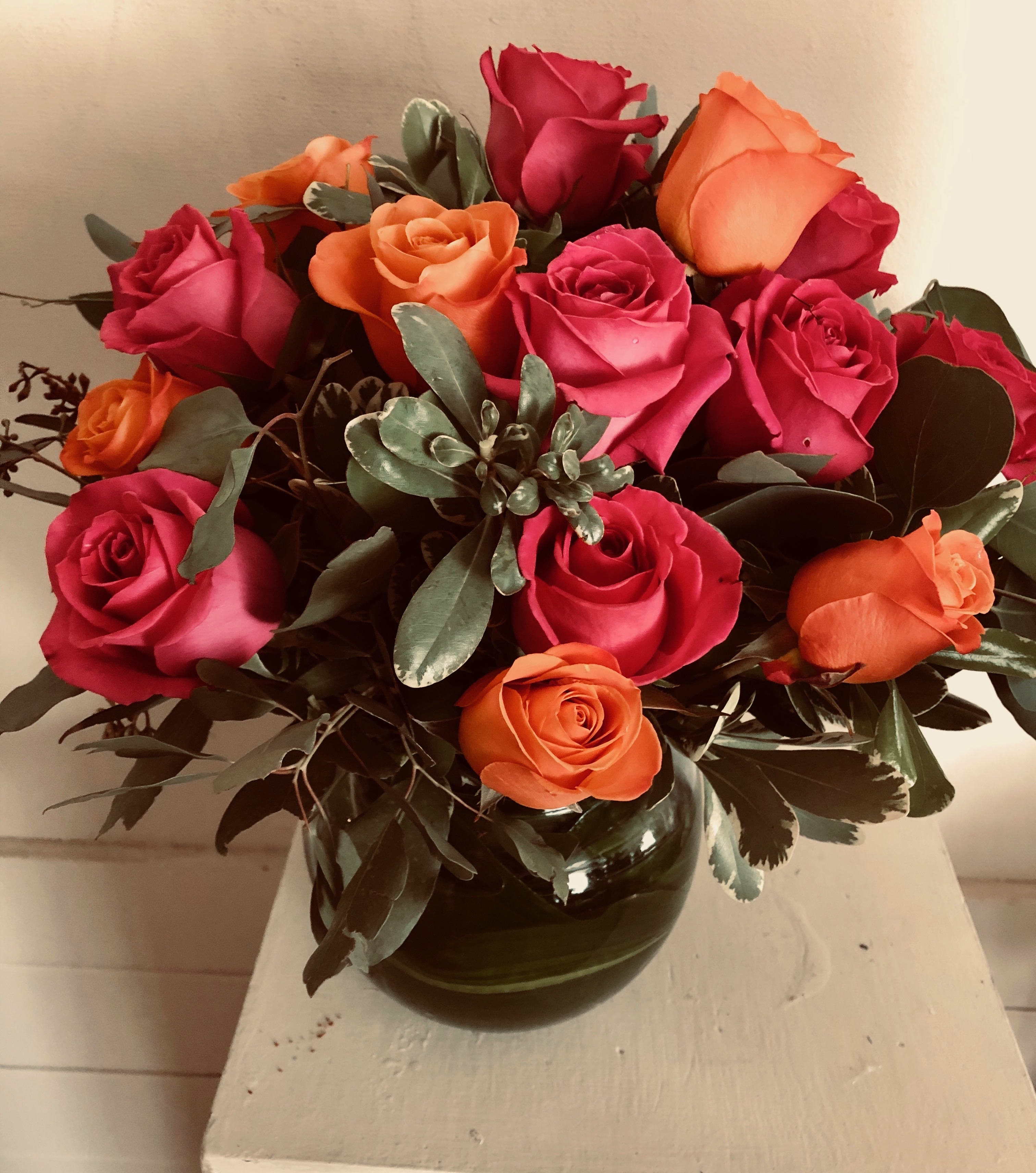 Contemporary Fall - Bubble bowl of orange and hot pink roses with a swirl of aspidistra leaf