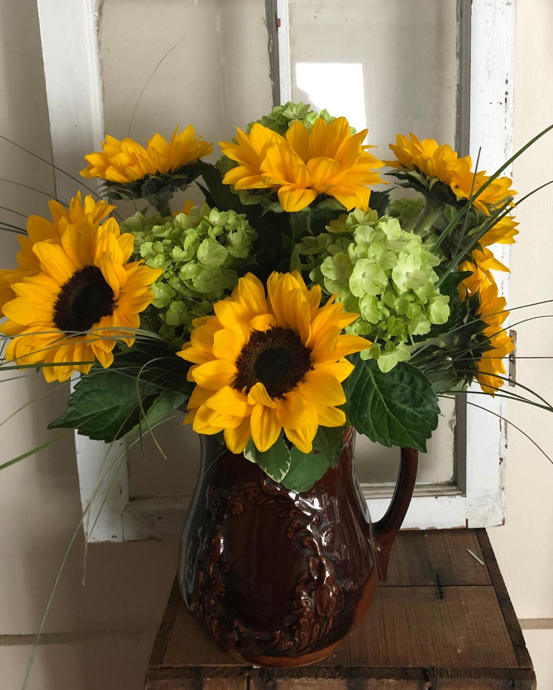 VINCENT - VINTAGE STONEWARE PITCHER (COLORS MAY VARY) FILLED WITH GORGEOUS , FULL SUNFLOWERS MIXED WITH GREEN HYDRANGEA AND BEAR GRASS.