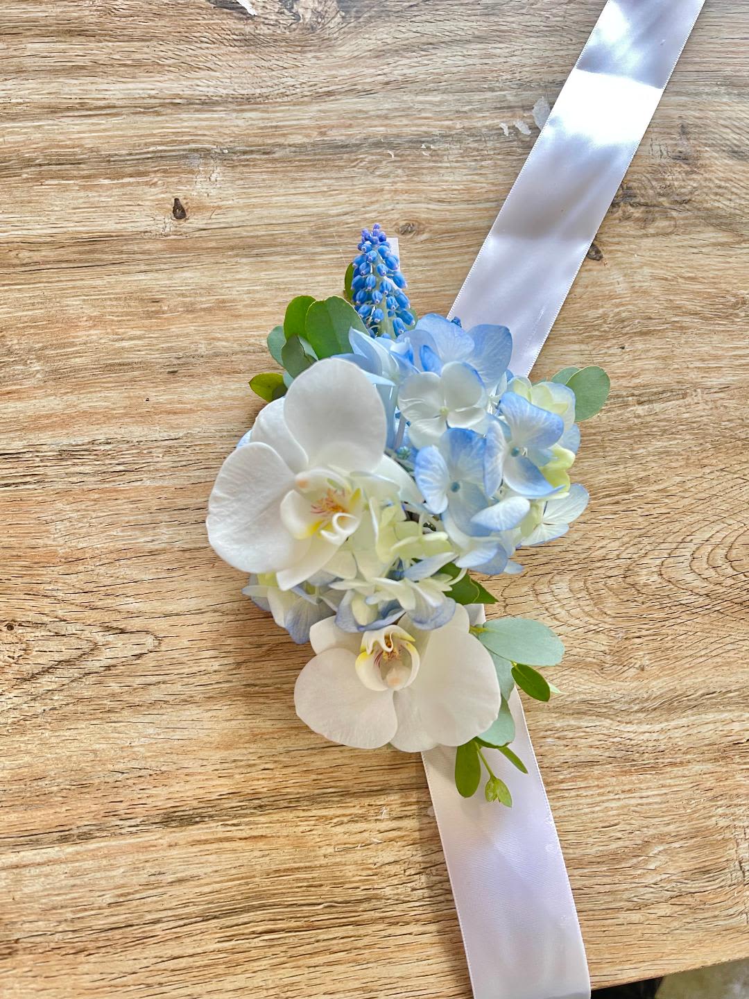 Sweet Serenity Corsage - Made from fresh flowers, a corsage looks like a petite flower arrangement (typically consisting of just one or several smaller blooms) and usually sits on the wrist like a bracelet, though it can also be pinned on a lapel. Corsages serve as a way to honor people who are very important to the couple getting married. Please contact our shop at (747) 249-4678 for any customization. 