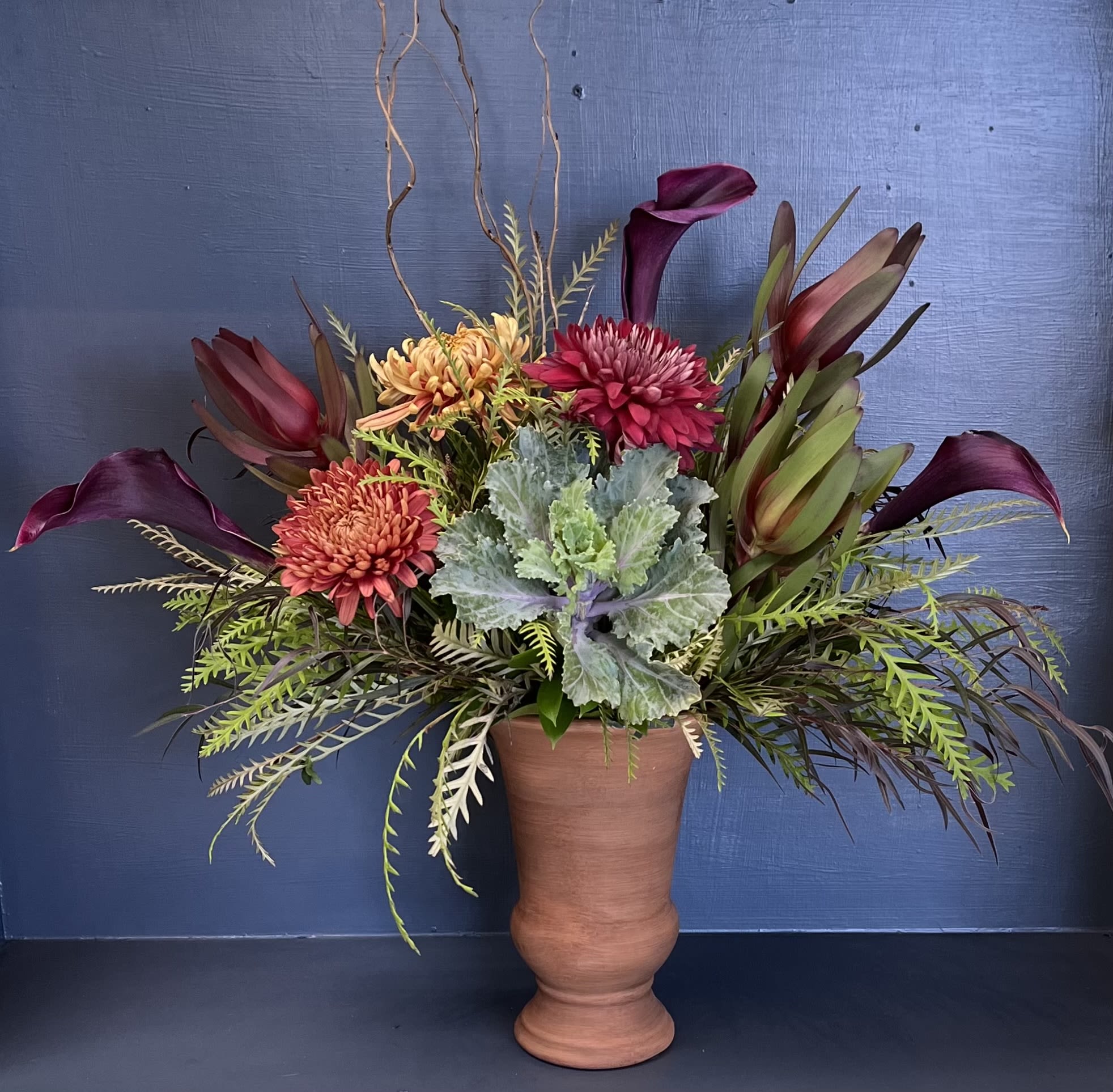 Warm Embrace Warm Embrace - A vividly crafted display, this arrangement uses a beautiful blend of kale, calla lilies and mums. Colors and vase may vary.