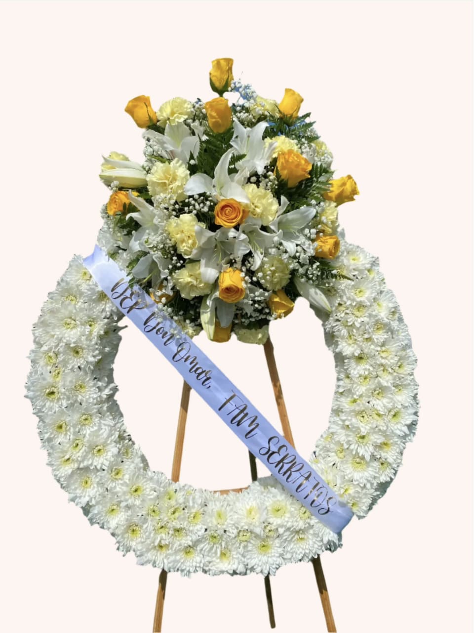 Peaceful Remembrance - A soft and serene wreath with white pom poms as the base, topped with yellow roses, lilies, carnations, and baby’s breath. A beautiful tribute symbolizing peace and lasting memories.  **Note: PICTURED IS THE PREMIUM SIZE.  Easel is INCLUDED**
