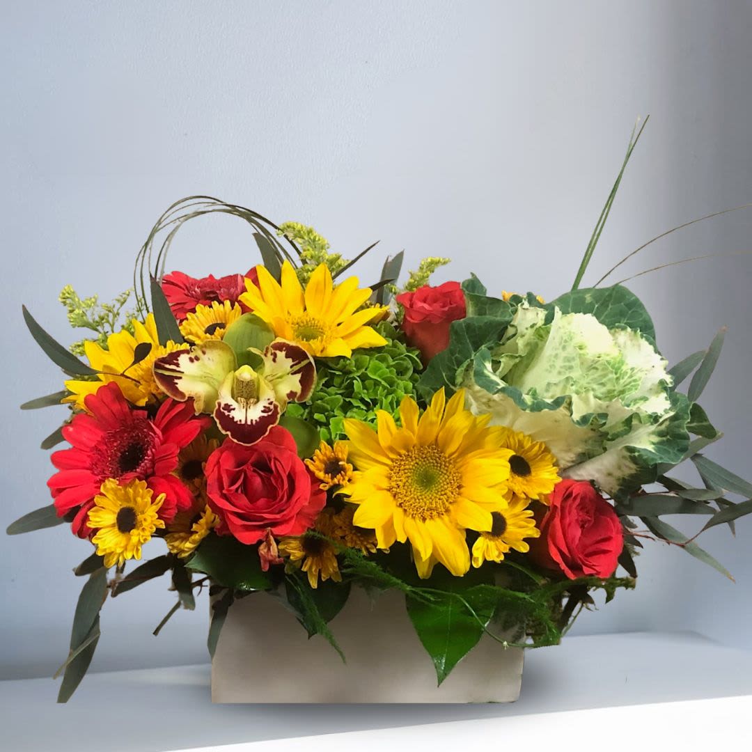 Sending Warmest Wishes - Type of Flowers: Green Hydrangeas, Yellow Cymbidium Orchid, Sunflowers, Red Gerbera Daisies, Blood-Red Roses, Yellow Daisies, and greens in a white ceramic vase. Availability: All year round Substitute Available: Yes Design View: Symmetric Front Facing View Photo shown: Standard 