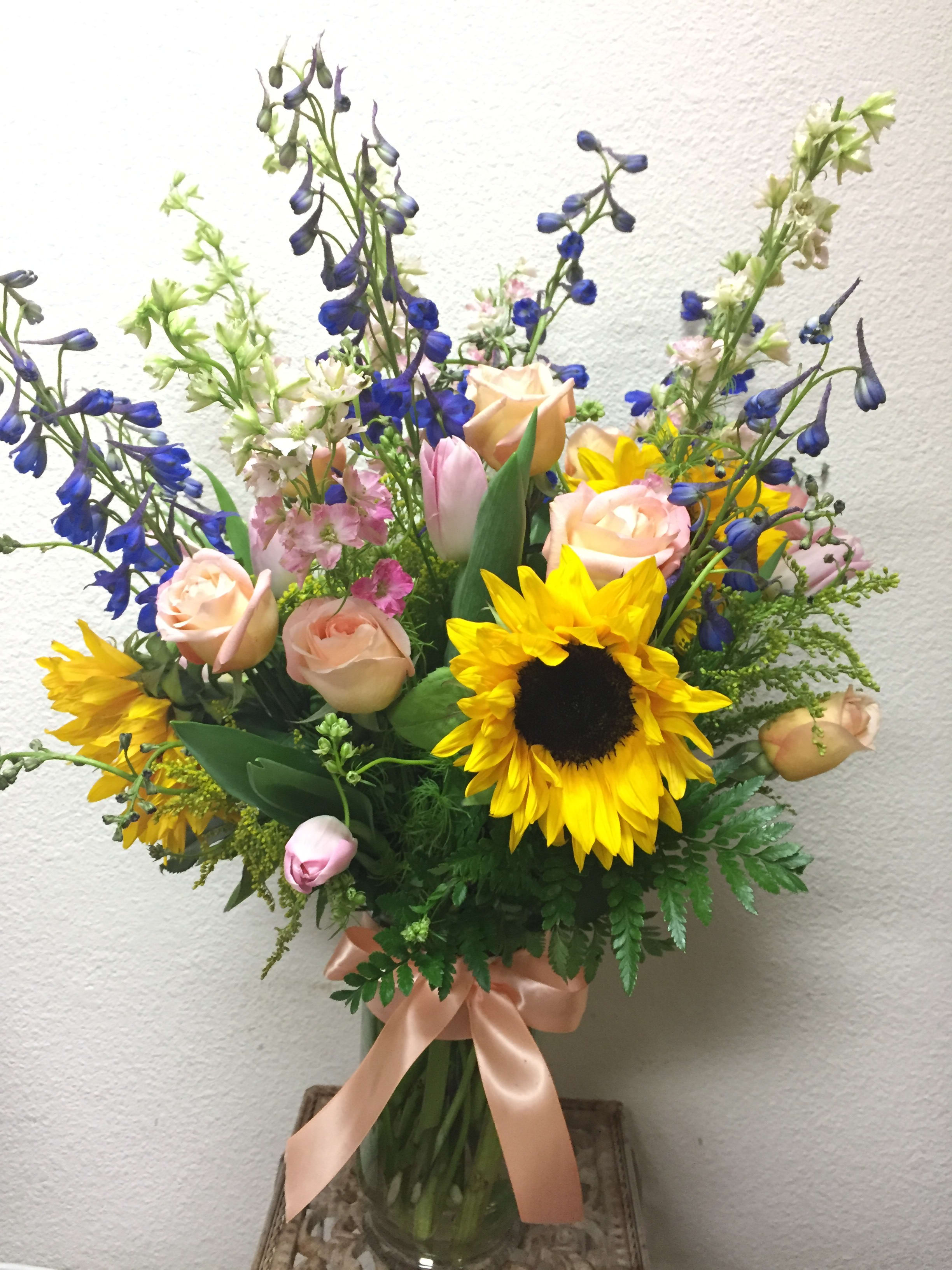 A Sweet Thank You - Send a thank you with these beautiful colors or roses, sunflowers and delphinium!  Seasonal: All year round Design View: Front Facing View Photo shown: Standard 