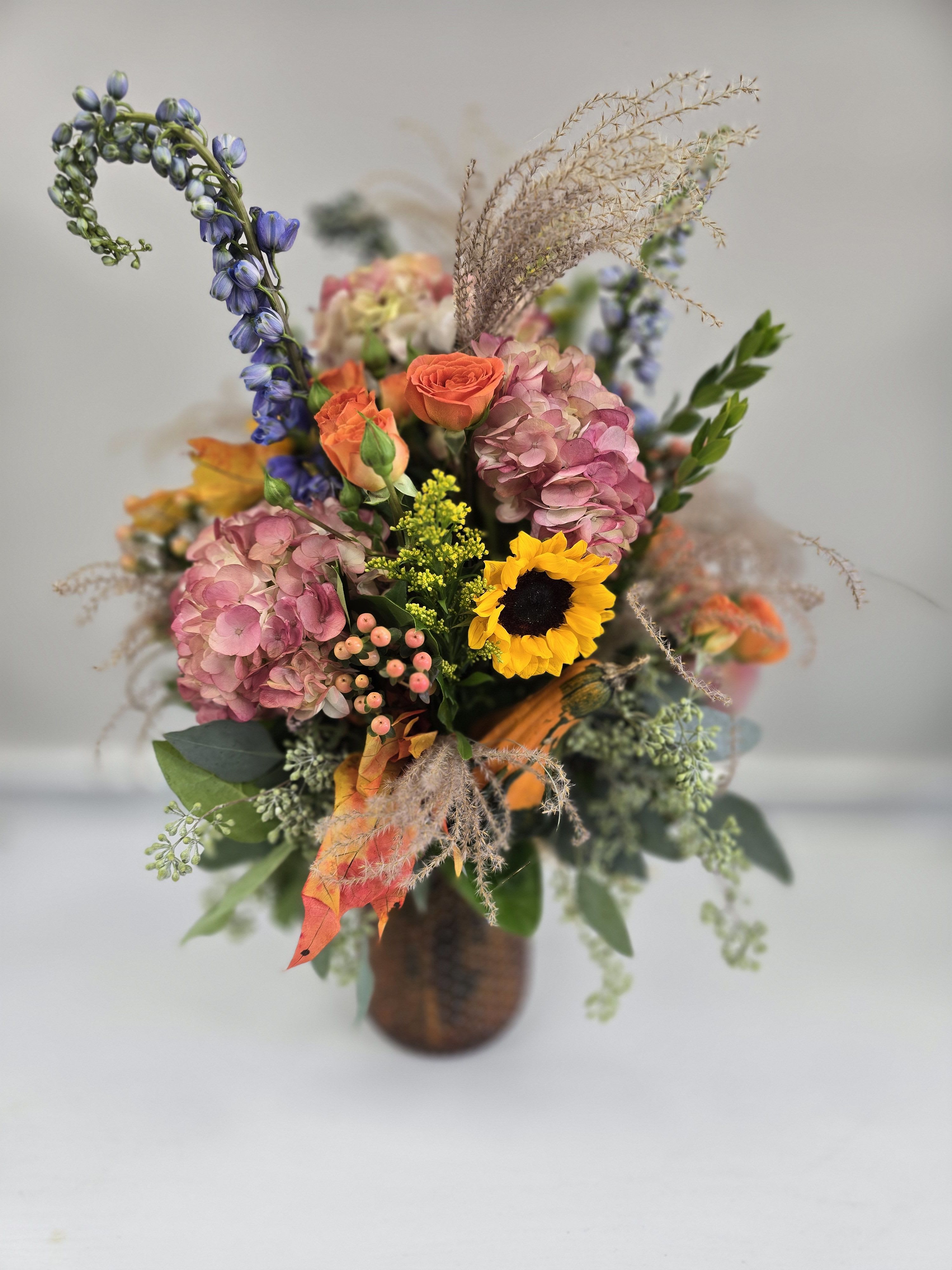 Autumn Sunset - Bring the beauty of an autumn sunset inside with this fall themed arrangement!   *Container and Flowers may differ slightly from what is shown in the picture depending on availability and season