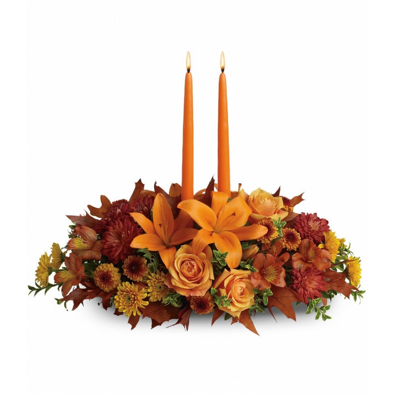 Family Gatherings Centerpiece - As your loved ones gather around the table, they'll bask in the warm glow of two orange taper candles surrounded by a fantastic array of fall flowers. Please note the bouquet pictured reflects our original design.  If the exact flowers or container in this arrangement are not available, will create a beautiful bouquet with the freshest available flowers.