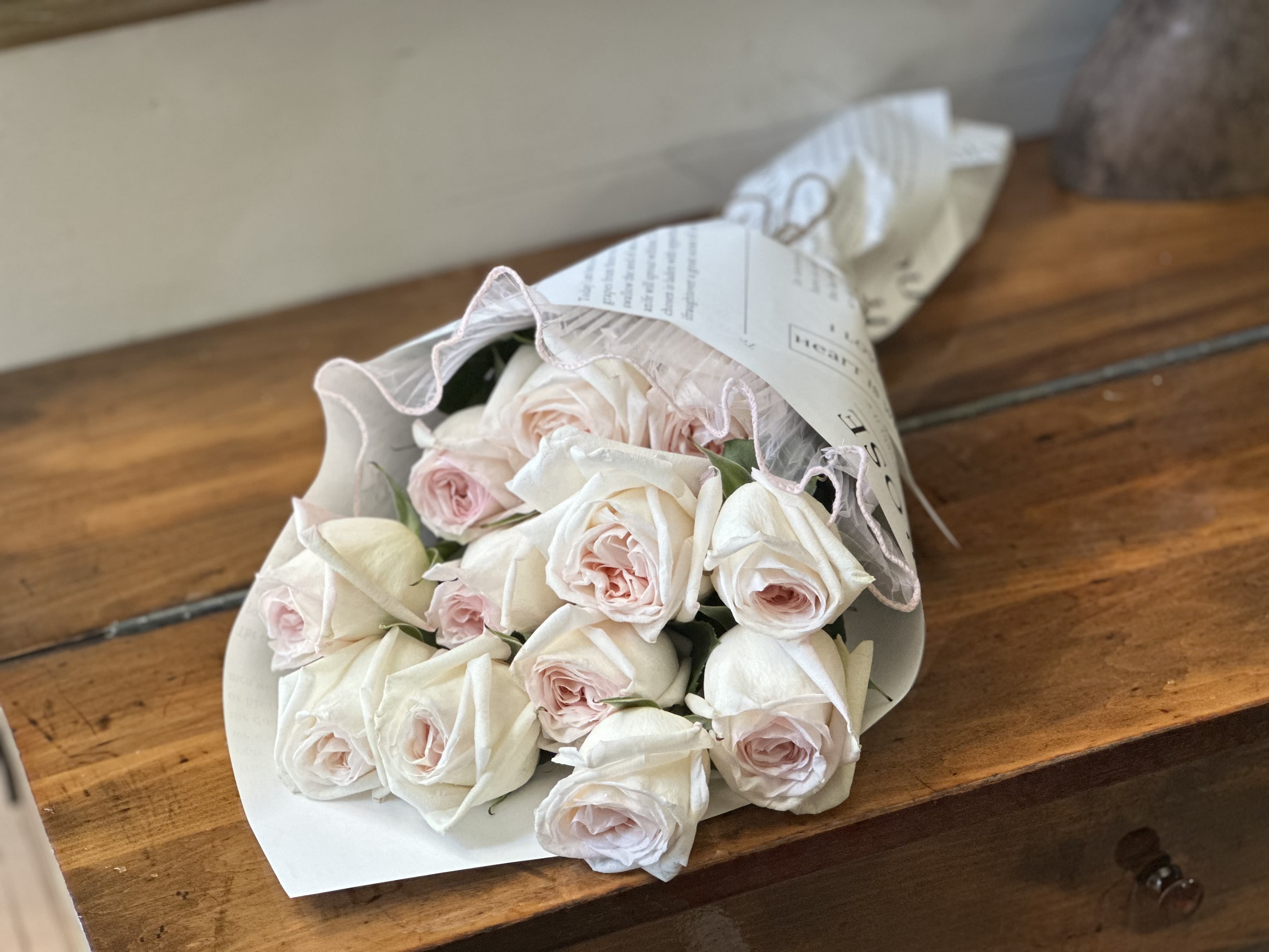 The Pure Dozen Bouquet  - Embrace natural beauty with our weekly organic rose collection. Each bouquet features twelve carefully selected organic roses, thoughtfully arranged and wrapped in elegant paper for a clean, minimalist aesthetic. Our roses are sourced fresh weekly, allowing the natural color variations to surprise and delight - from soft blush and cream tones to deeper romantic hues. Without added greenery, the focus remains purely on the organic roses themselves, showcasing their natural form and delicate fragrance. Perfect for those who appreciate sustainable floriculture and understated elegance. Each bouquet celebrates the authentic beauty of roses as nature intended - no two arrangements are exactly alike, making every delivery a unique gift from earth to home. The simple paper wrap keeps the presentation clean and allows the roses to be easily transferred to your favorite vase, where their natural beauty can truly shine. Rose life is up to 5 days with upkeep of clean water and trimming every 2/3 days. 