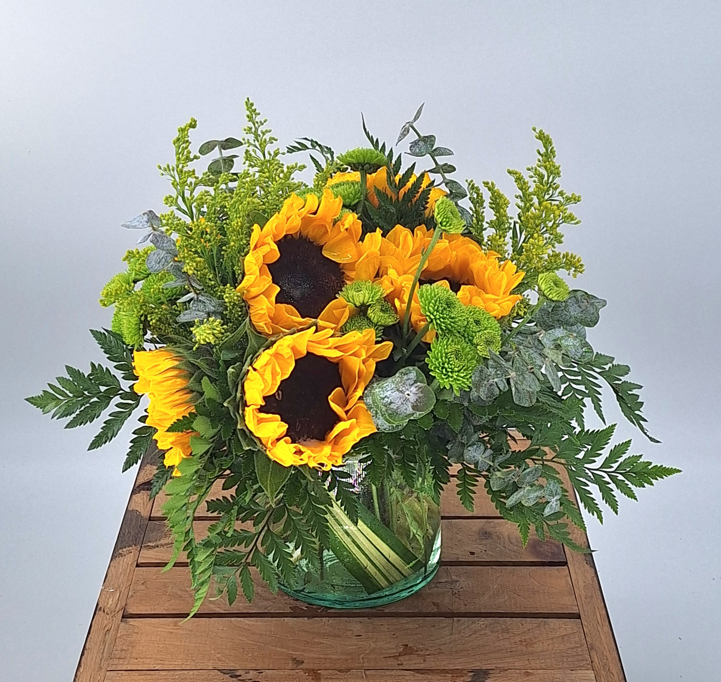 Sunflower Power (BR) - Introducing our cheerful and vibrant flower arrangement featuring sunflowers in a leaf-lined cylinder vase. This stunning display is a true celebration of the beauty and warmth of the sun.  