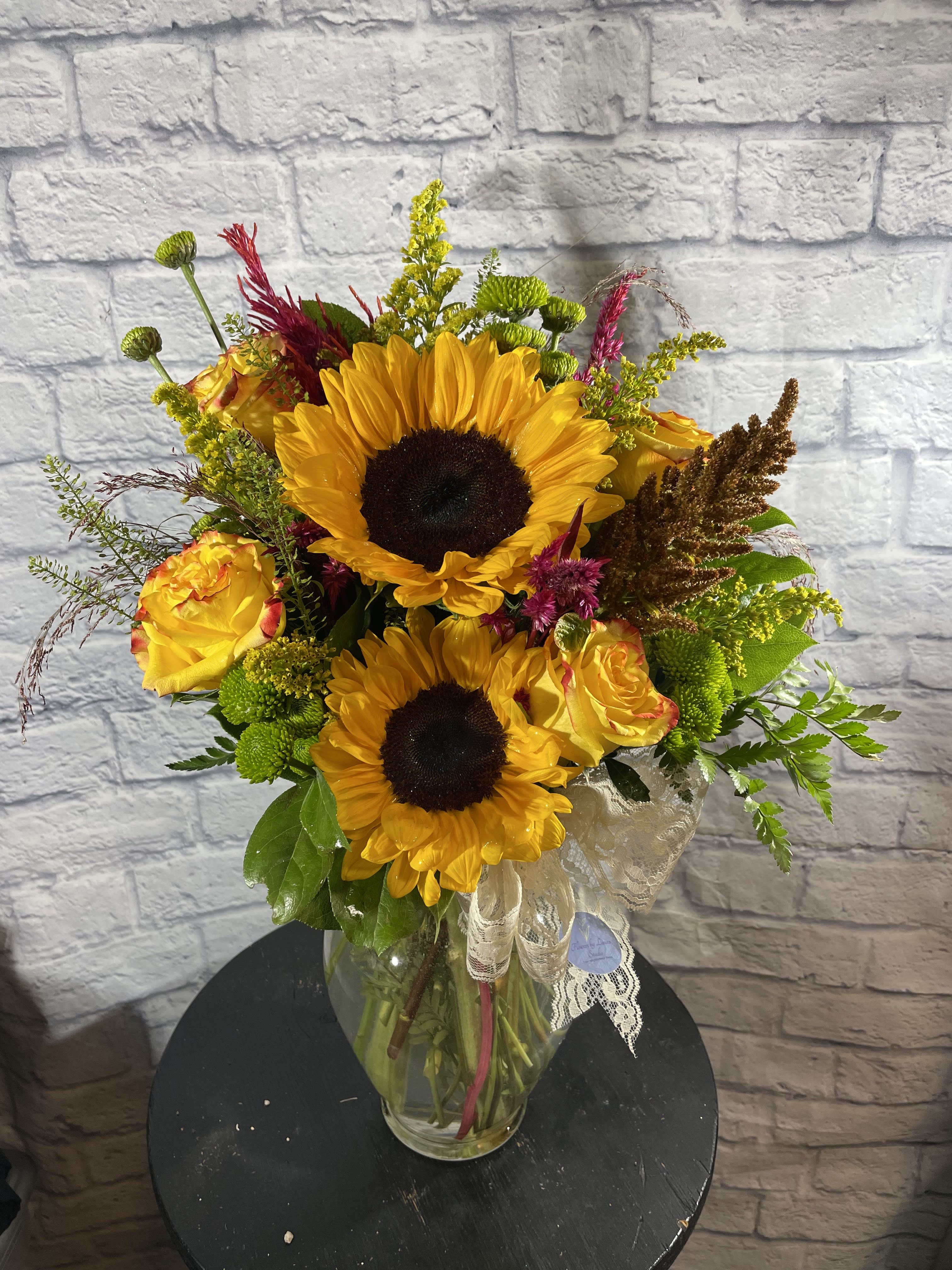 Golden Hour - This assortment of flowers remind me of that perfect time at dusk called &quot;Golden Hour.' This bouquet has a variety of fresh seasonal flowers and SUNFLOWERS. It comes with locally grown sunflowers (when available and may vary in colors: regular yellow, red, or teddy bear variety) and fresh greenery.   We love to give our artists the ability to put together arrangements as they see best, Flower type and vase may vary. (Depending on inventory, flowers could come in a basket or a vase.)  Proud to deliver to Nibley, Hyrum and Wellsville area. 