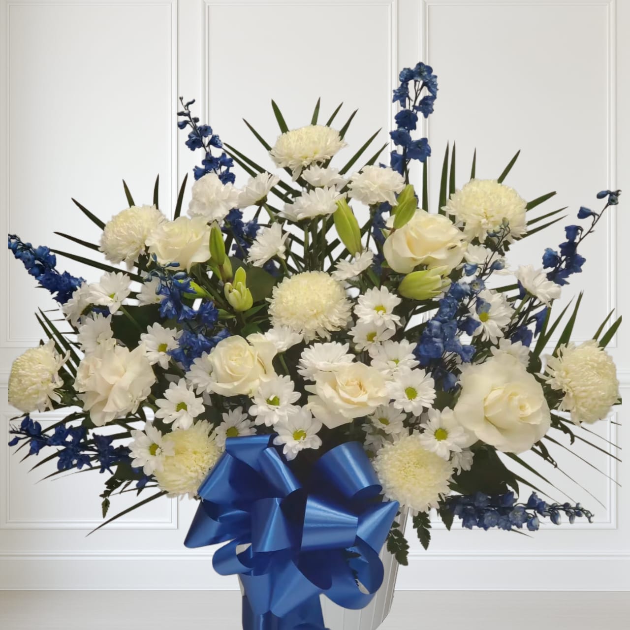 Blue and white floor basket Blue and white floor basket - This blue and white floor basket includes 8 white mums, 8 blue delphinium, 8 white daisy, 2 white carnations and 2 white lilys