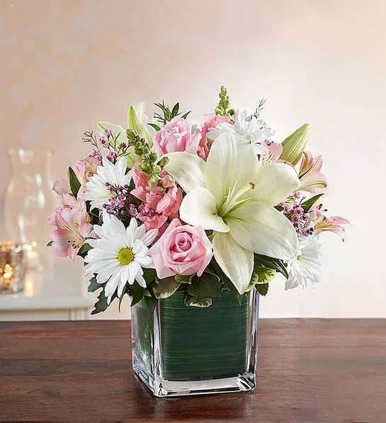 Healing Tears - Pink &amp; White - Delicate blooms call to mind beauty, grace and sweetness—a reminder of the dearly departed themselves. Our sympathy arrangement of gentle pink roses and white lilies, expertly gathered in a clear glass cube lined with a Ti leaf ribbon, makes for an exquisite gesture of comfort and healing. 