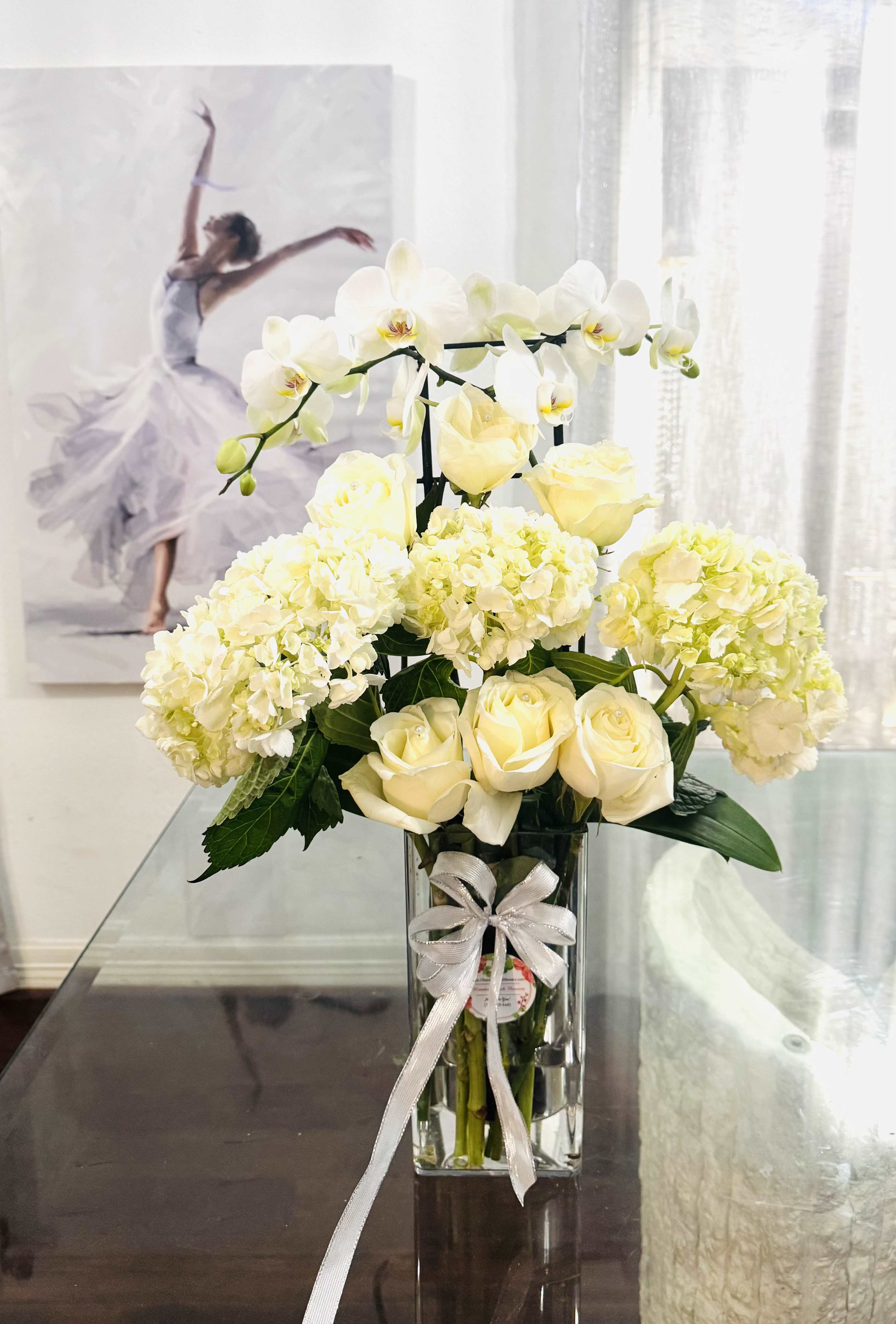 Orchid decorated Orchid decorated - A poetic dance of purity and grace, captures the essence of elegance in full bloom. This Vertical masterpiece features with delicate white orchids, white roses and voluminous white hydrangeas. Arranged in a vase, the bouquet echoes the refinement of a classical performance- serene, structured, and full of emotional light. Perfect for any occasion, simply to bring serenity and sophistication into any space. A true floral symphony- soft, radiant, and unforgettable.