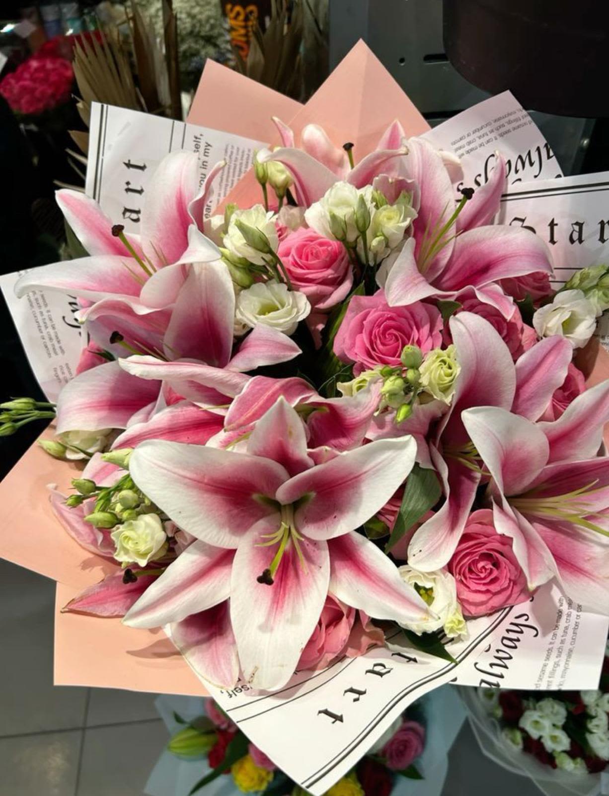 Blush Elegance Wrapped  - A radiant bouquet that speaks the language of grace and affection, Blush Elegance features starry pink-and-white lilies harmoniously intertwined with delicate pink roses and lisianthus. The soft gradient petals and fresh blooms exudes charm and sophisticated, all wrapped in artistic paper with subtle script accent. This bouquet is perfect for expressing love, admiration, or heartfelt congratulations in the most elegant way.